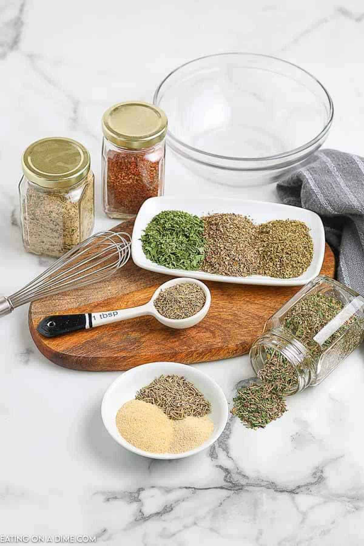 Combining the dried seasoning together in a bowl with jars of seasoning on the side