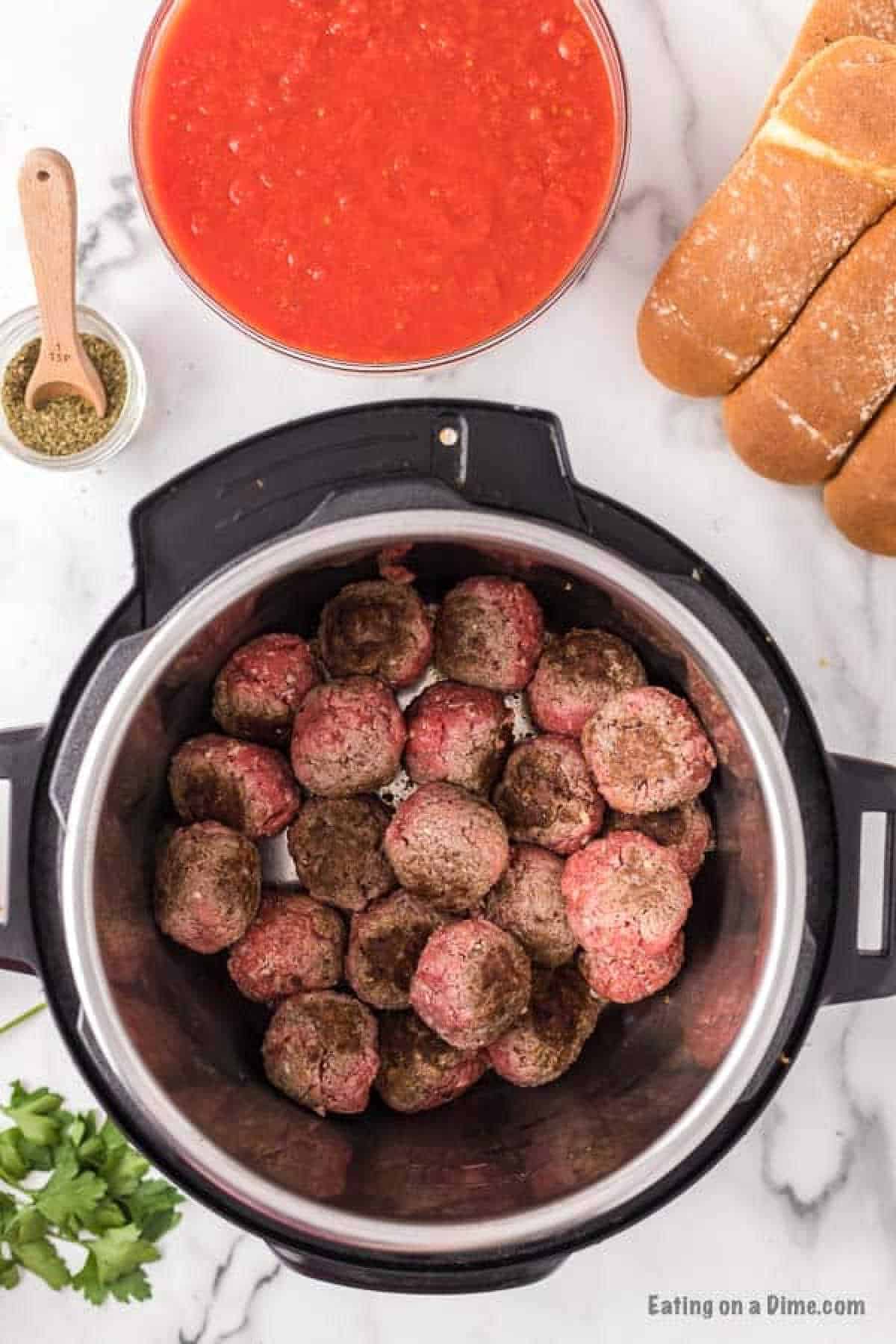 Browned meatballs in the instant pot with a bowl of sauce and seasoning on the side