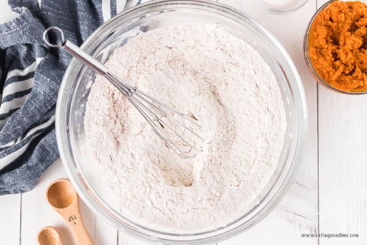 Combining flour with the other dry ingredients in a bowl with a whisk