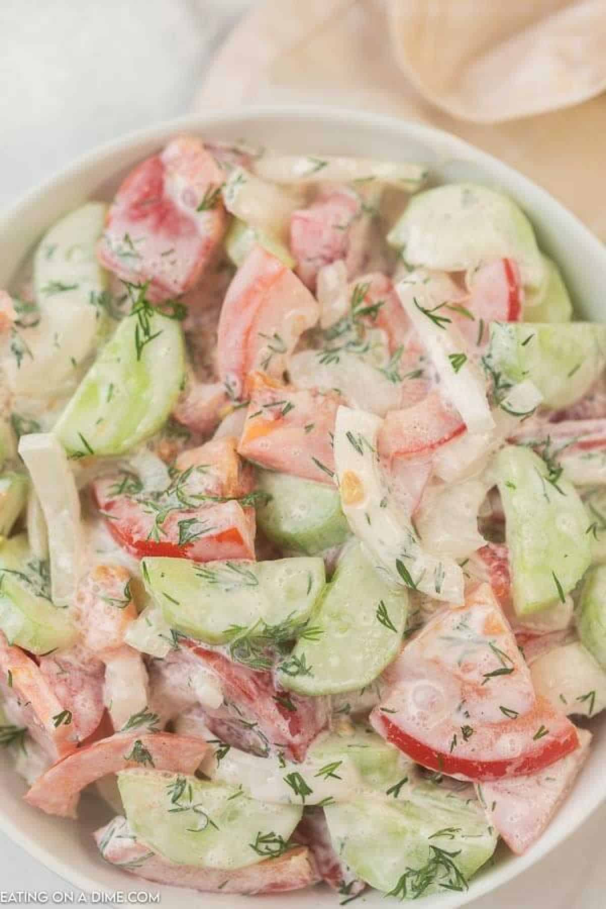 creamy cucumber and tomato salad in a white bowl.