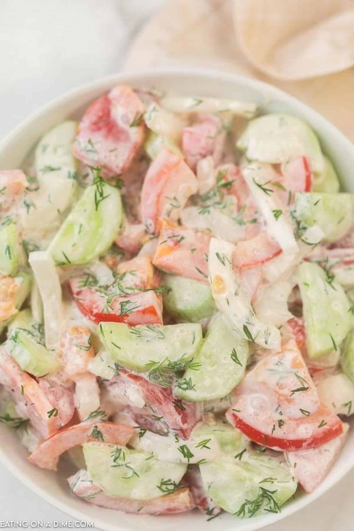 creamy cucumber and tomato salad in a white bowl.