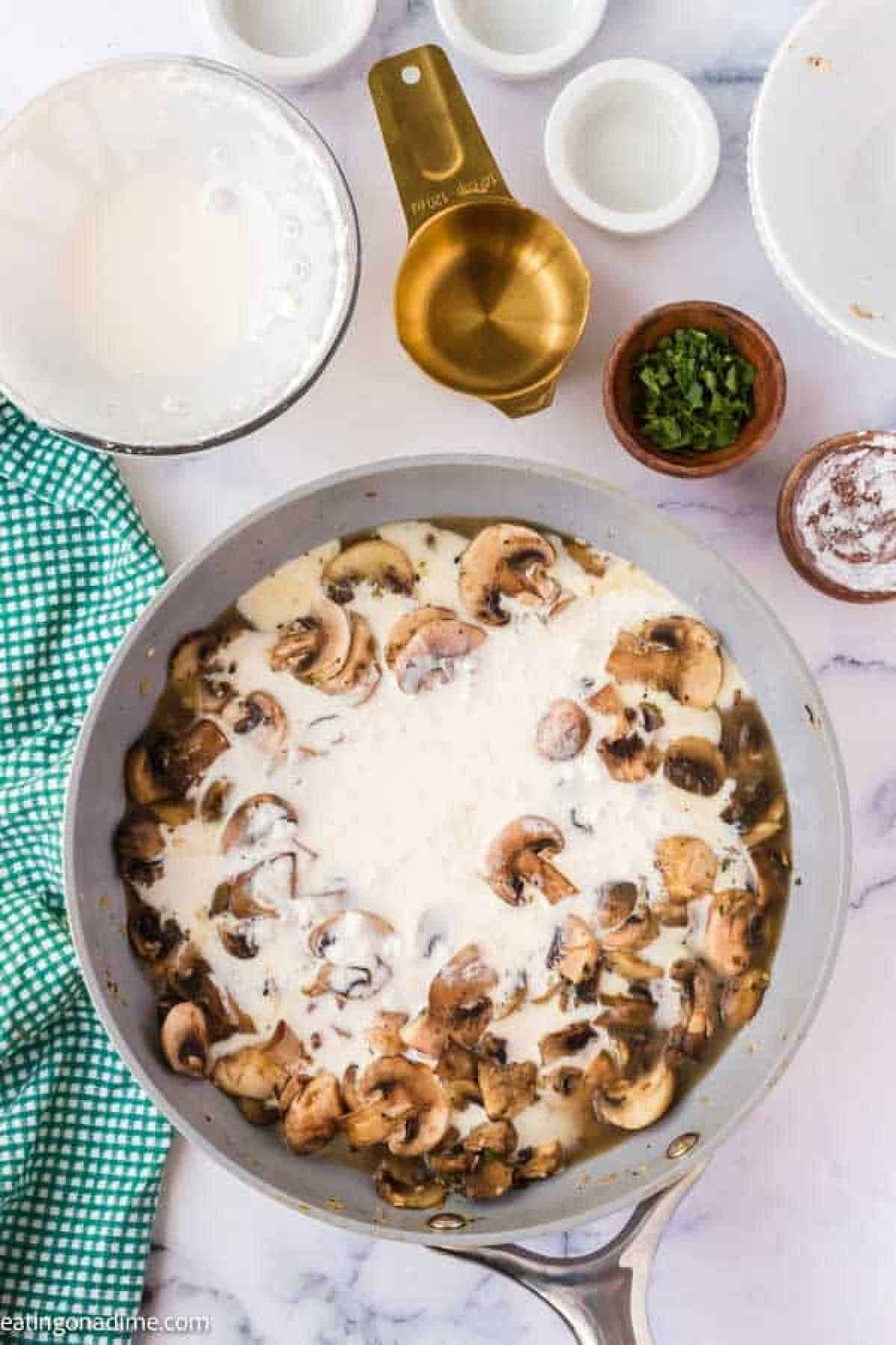 Pouring the heavy whipping cream mixture into the slice mushrooms in a skillet