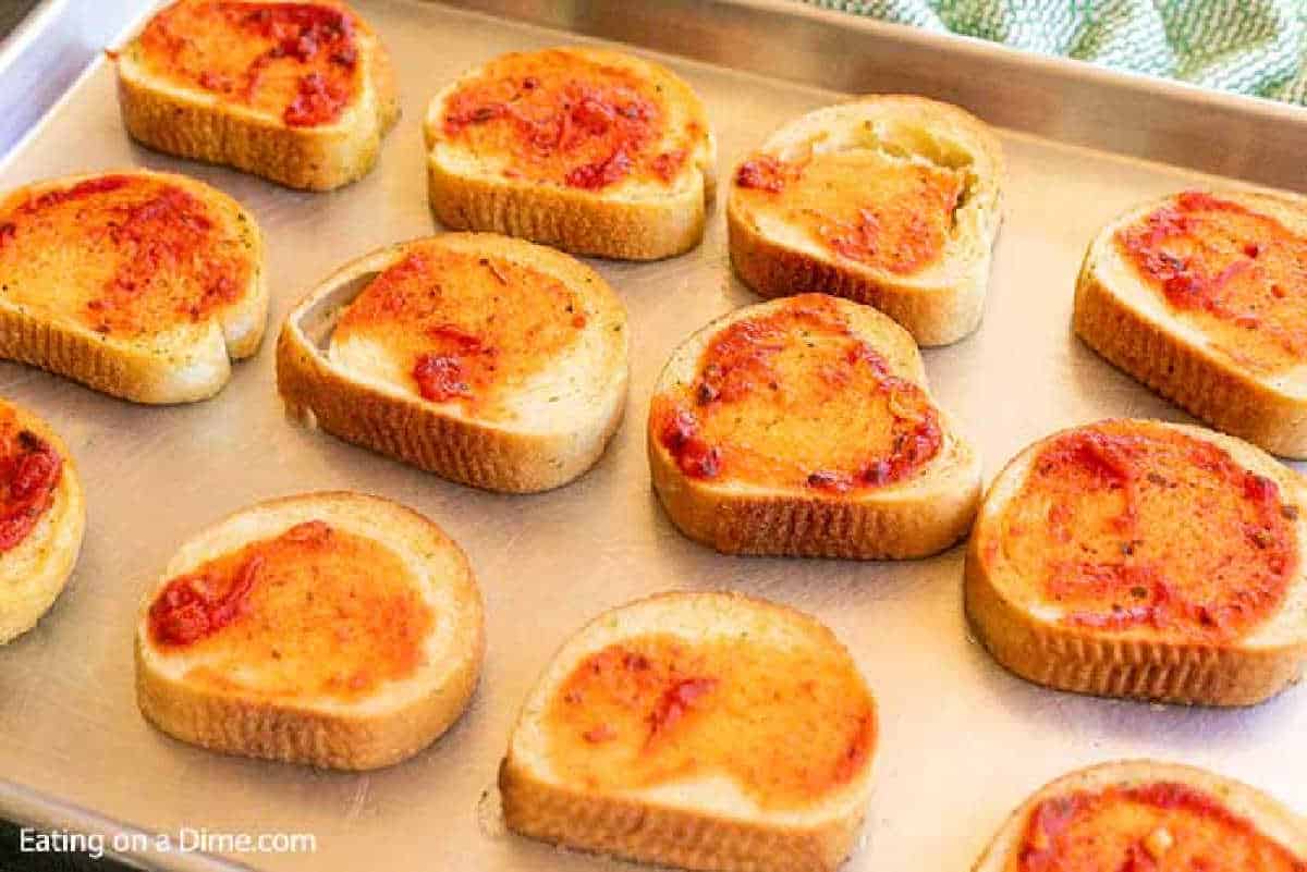 Brushing pizza sauce over the Texas Toast on the baking sheet