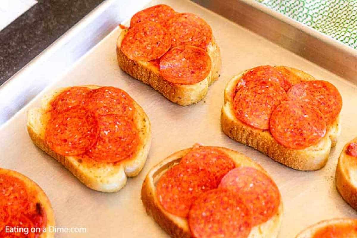 Topping the Texas Toast with Slice Pepperonis on baking sheet