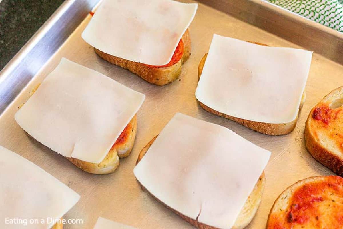 Topping Bread with Slice of Mozzarella Cheese on a baking sheet