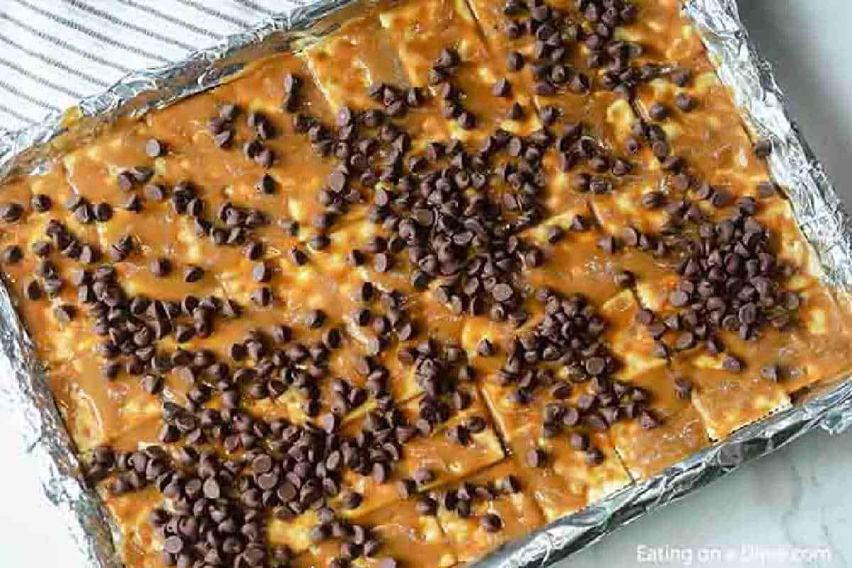 Brown Sugar mixture over crackers on a foil lined baking sheet topped with chocolate chips