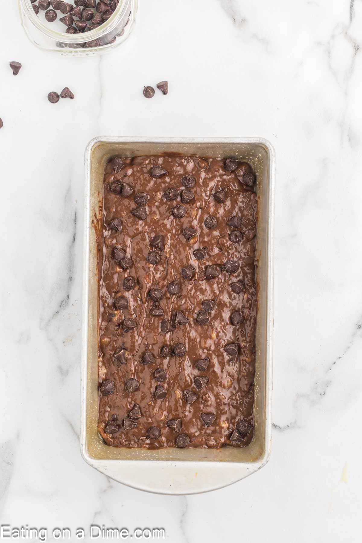 Chocolate banana bread batter in a loaf pan topped with chocolate chips