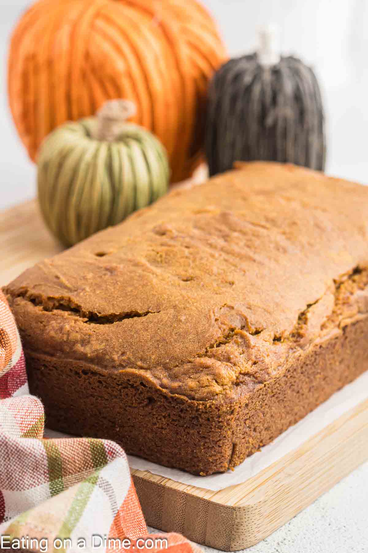 Loaf of Pumpkin Bread on a cutting board with decorative pumpkins in the background