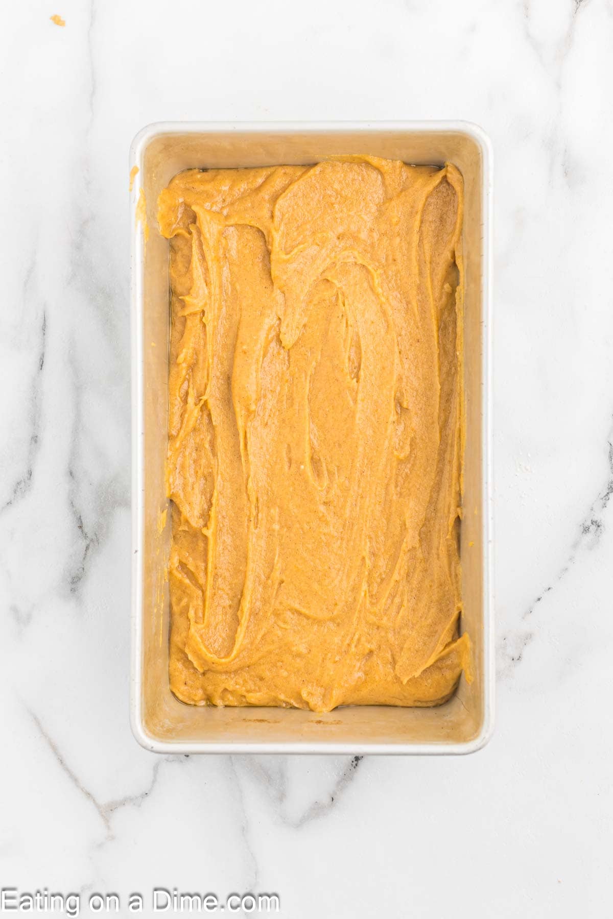 Spreading the pumpkin bread batter in a loaf pan