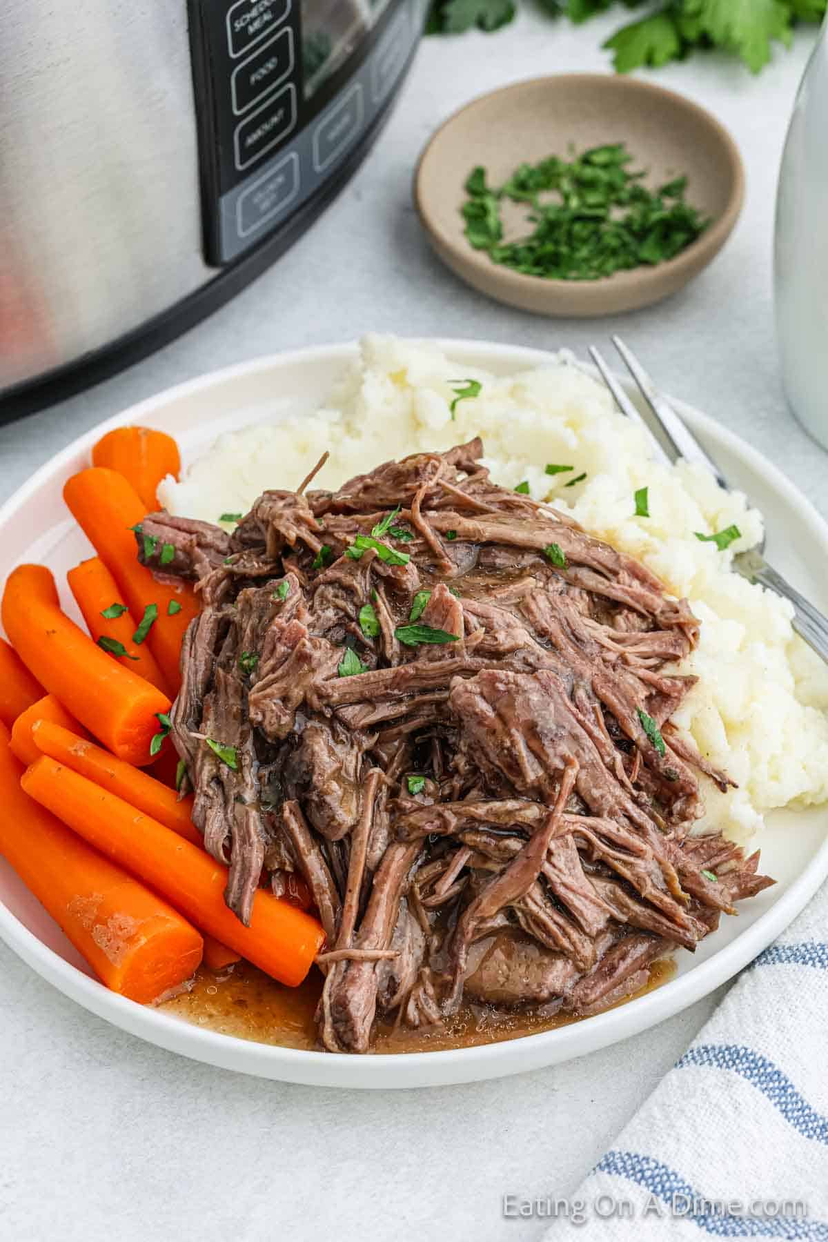 Shredded roast on a plate with mashed potatoes and carrots