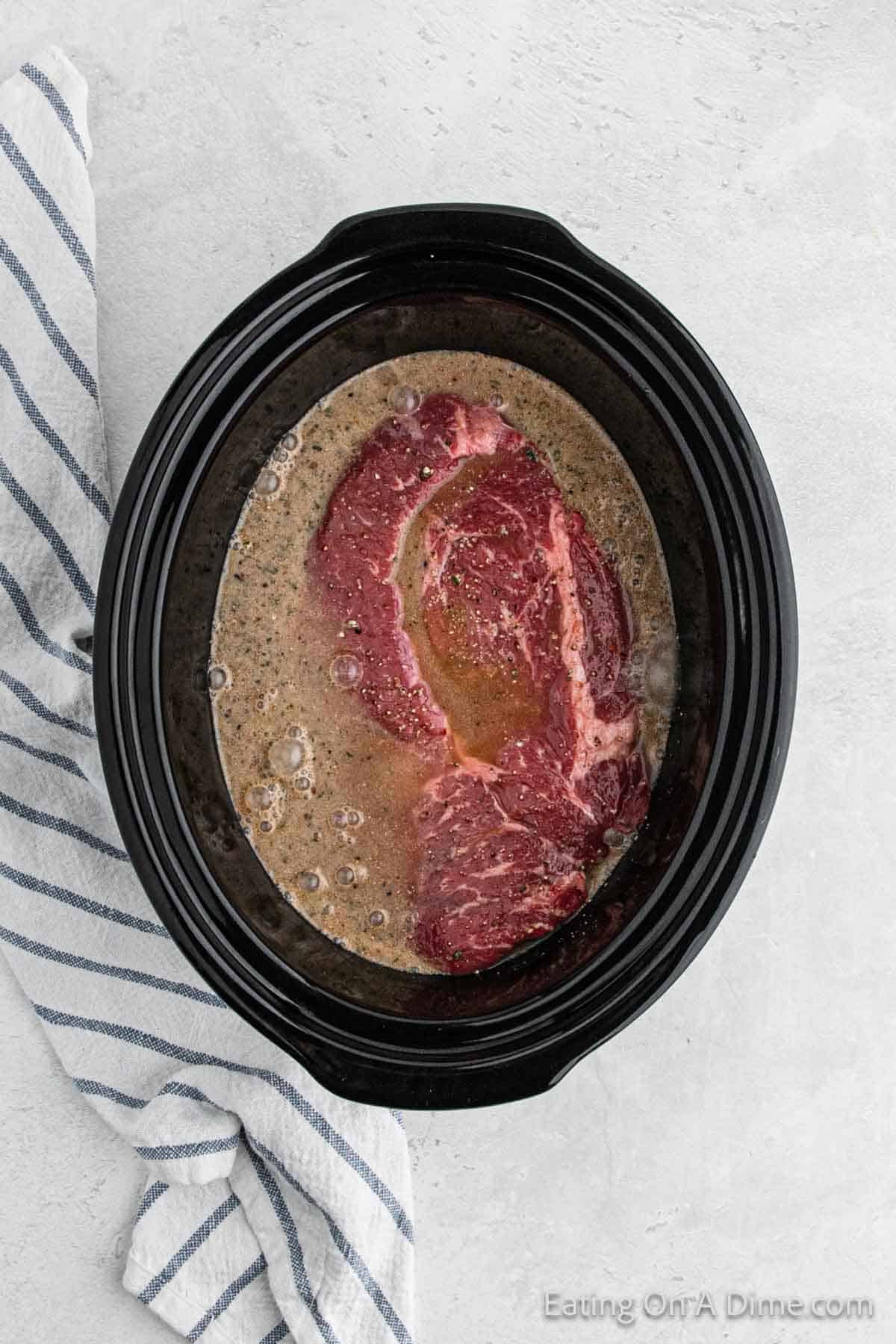 Pouring the seasoning mixture over the roast in the slow cooker