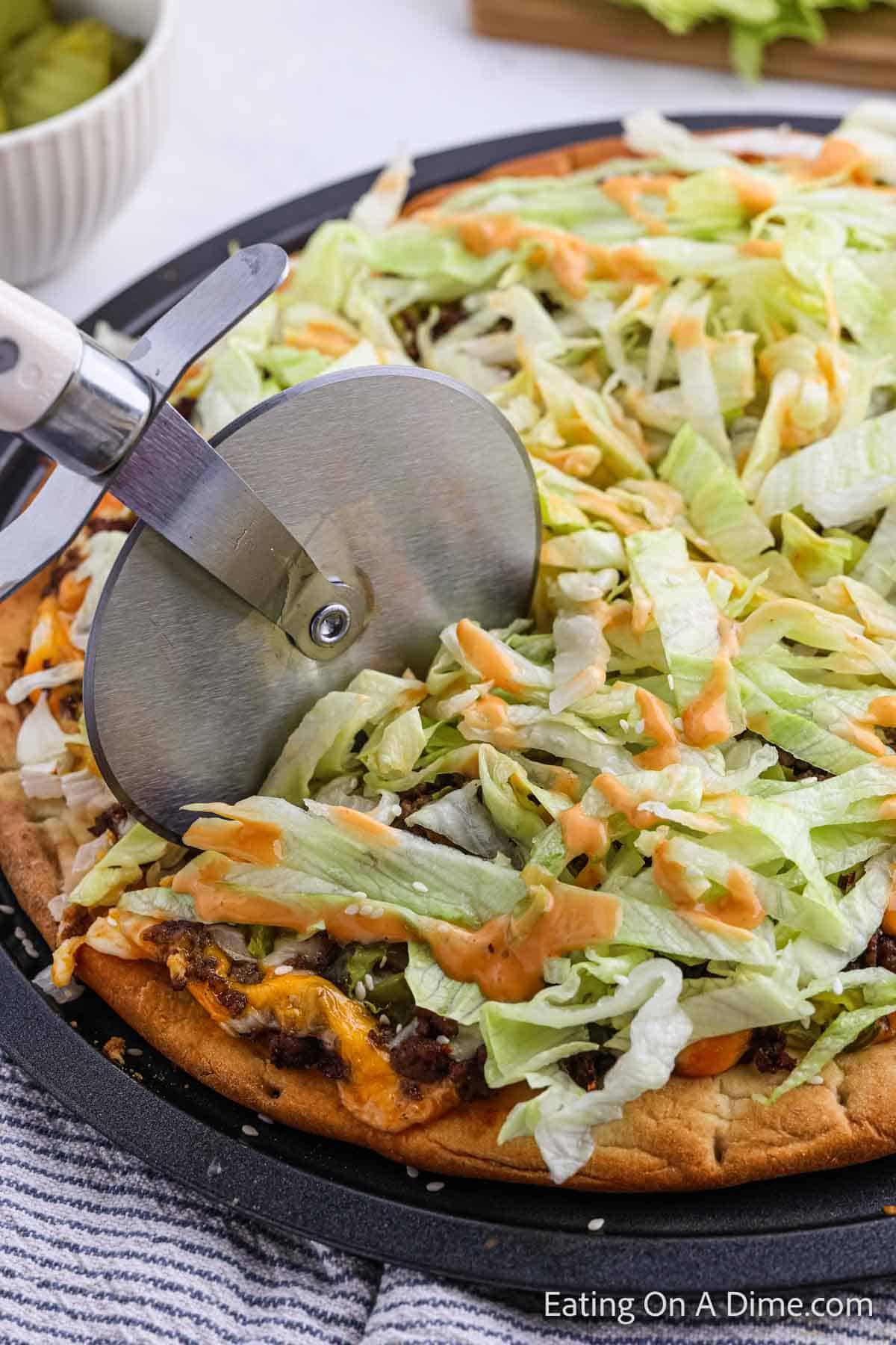 Big Mac Pizza being cut with a pizza cutter