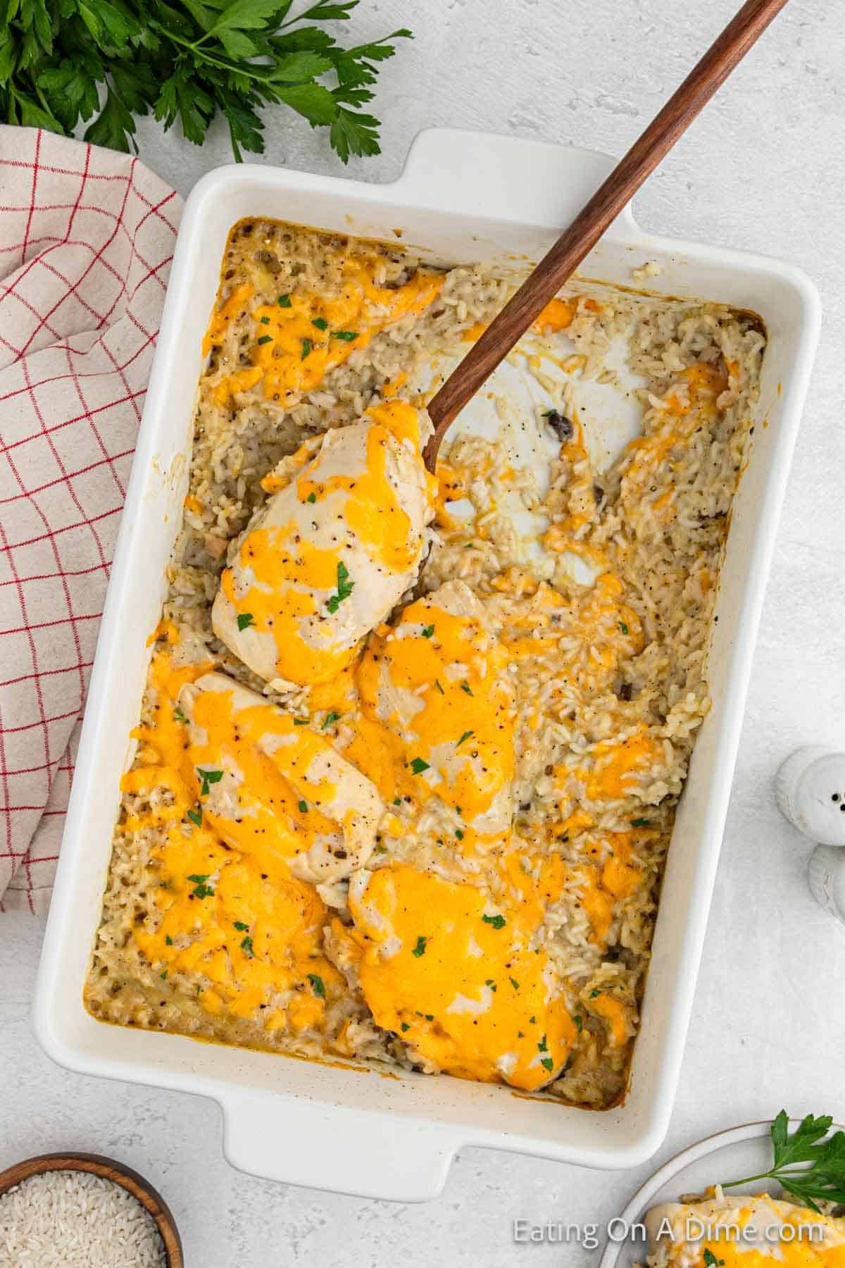 Chicken, Rice in the casserole topped with melted cheddar cheese with a serving on a wooden spoon