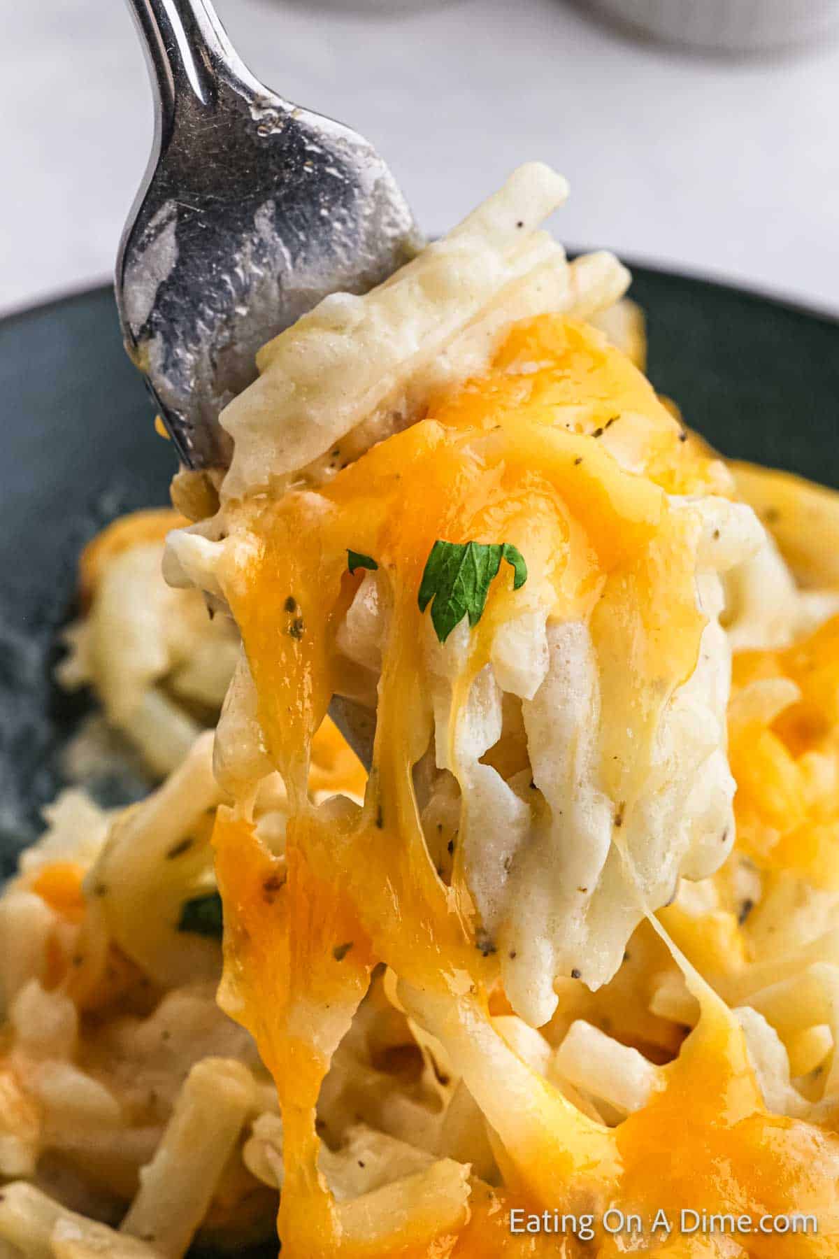 Hashbrown casserole topped with cheese with a bite on a fork