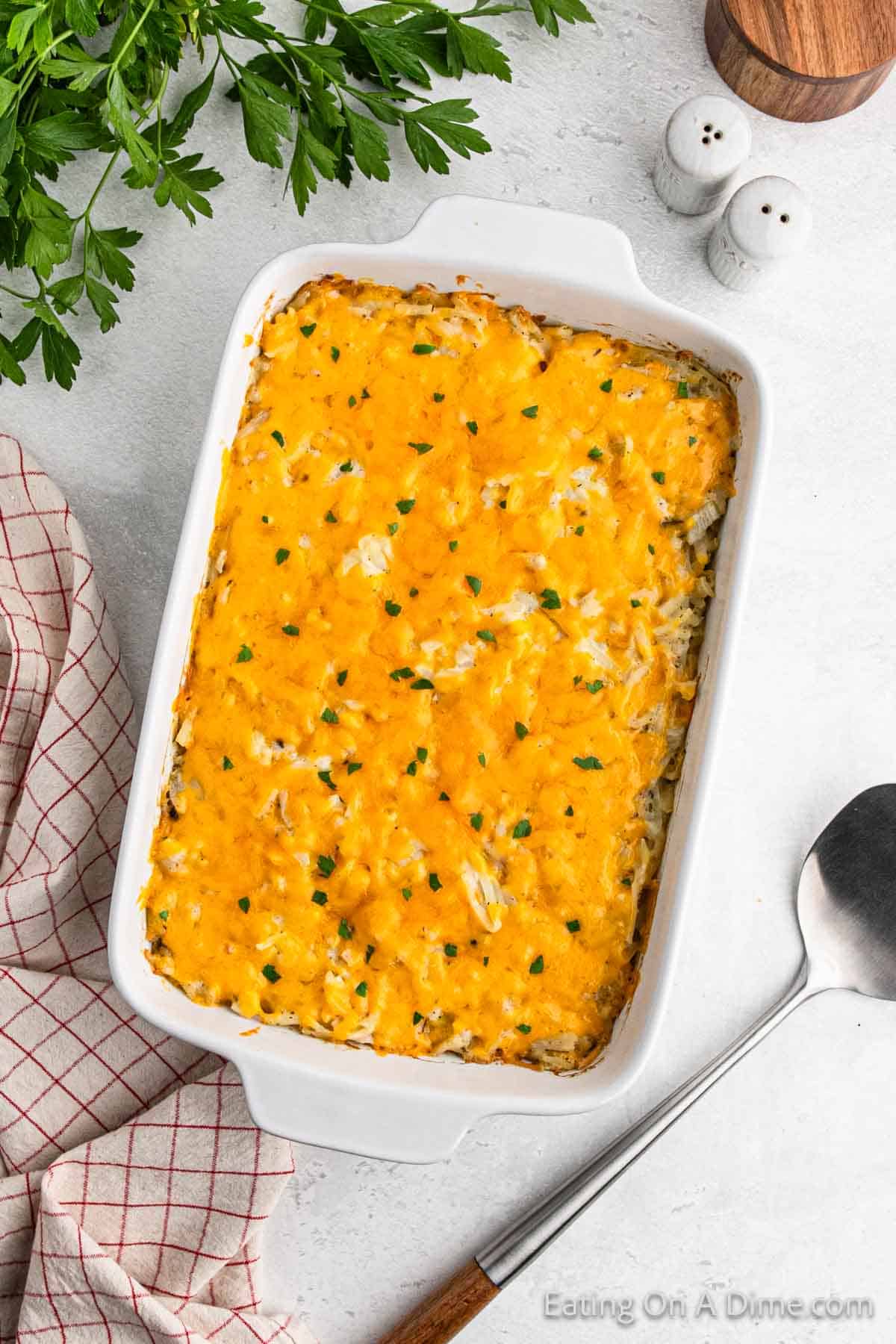 Hashbrown Casserole topped with melted cheese in a white casserole dish