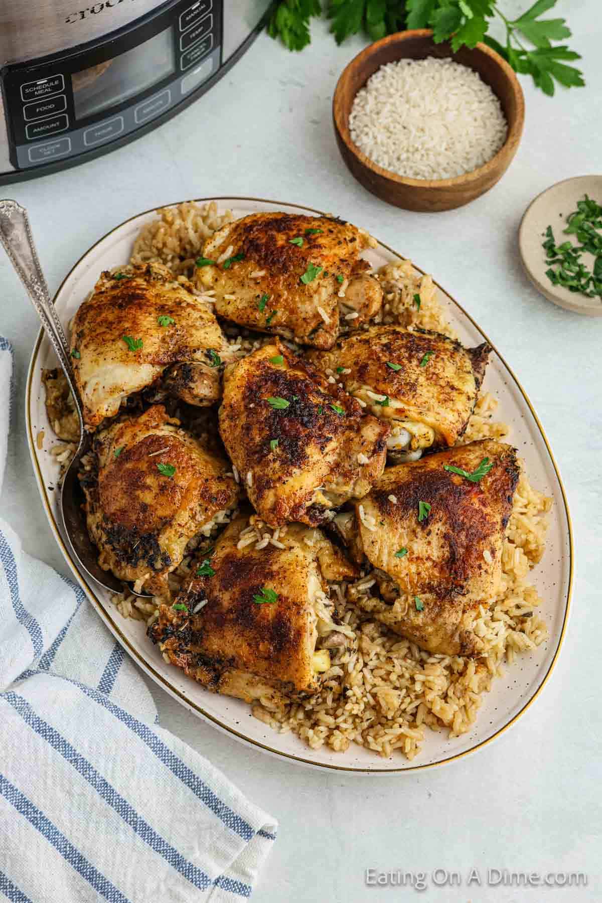 Golden brown chicken thighs on a platter with cooked rice on a platter