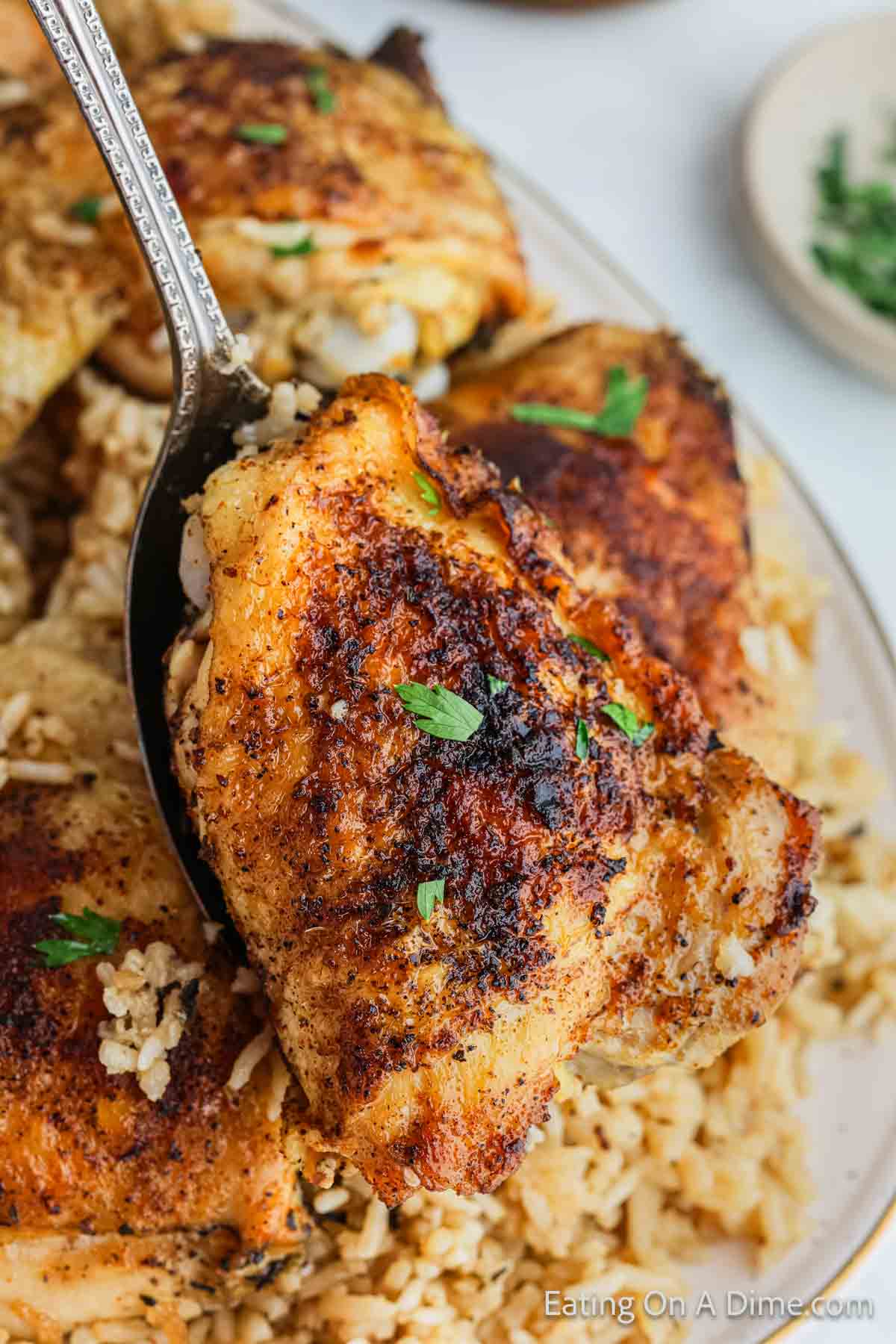 Golden Brown chicken thighs on a platter with rice on serving spoon