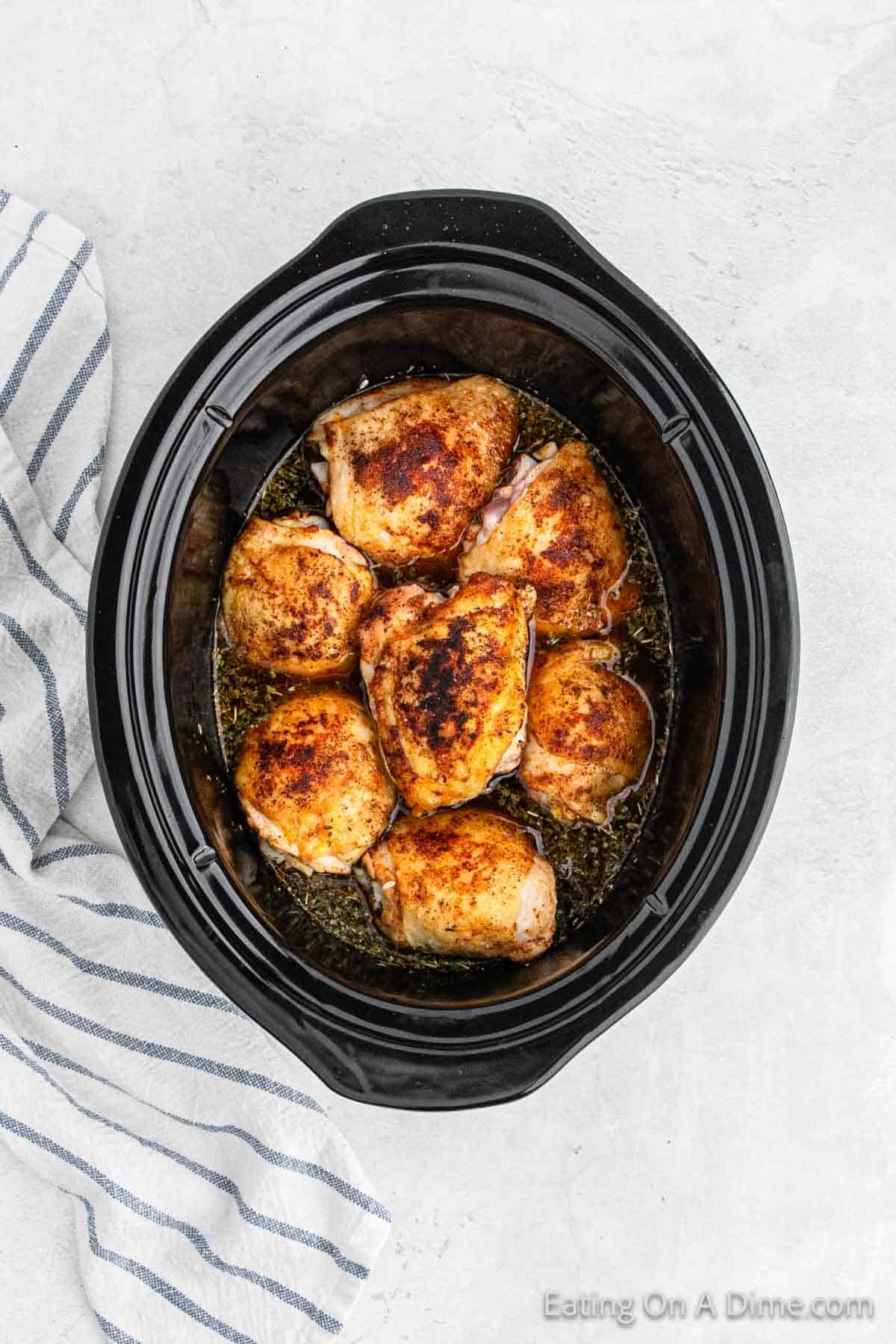 Cooked golden brown chicken thighs in sauce in the slow cooker