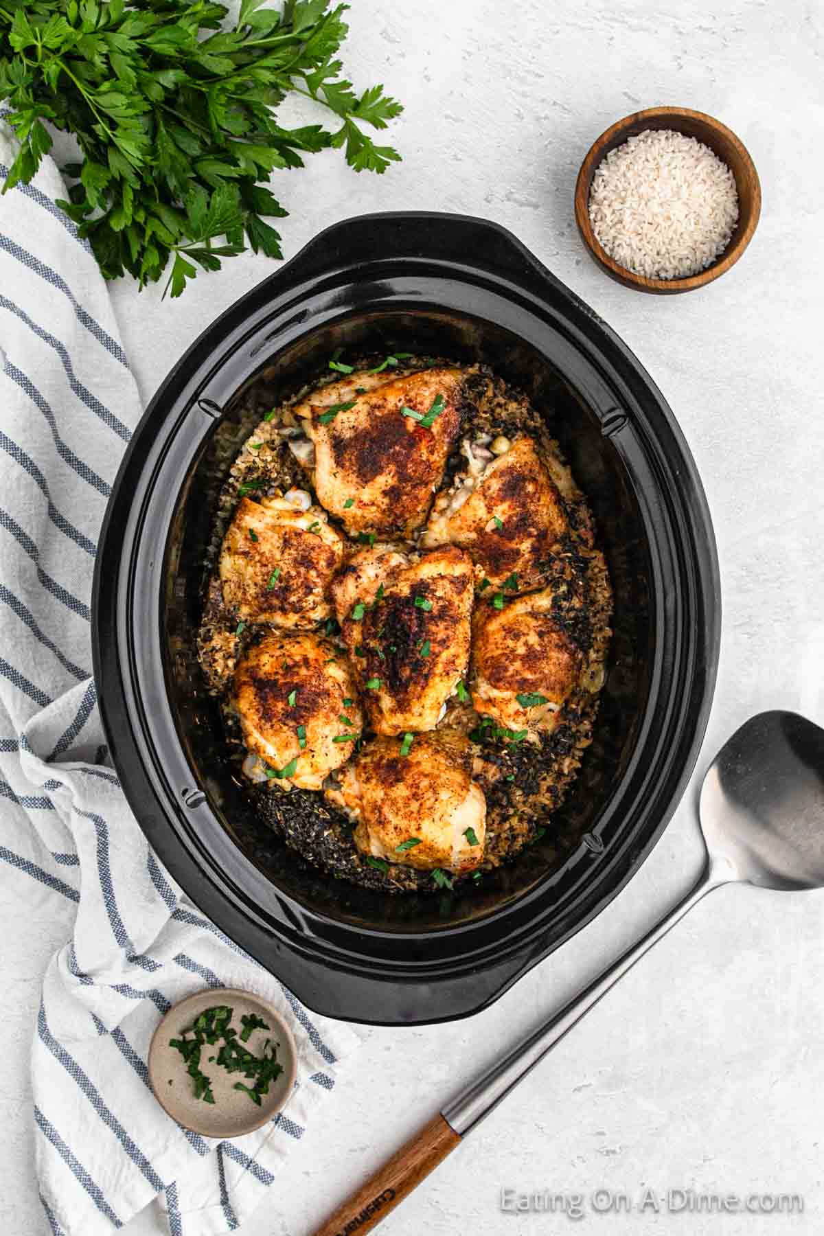 Golden brown chicken thighs in slow cooker with a side of uncooked rice in a bowl