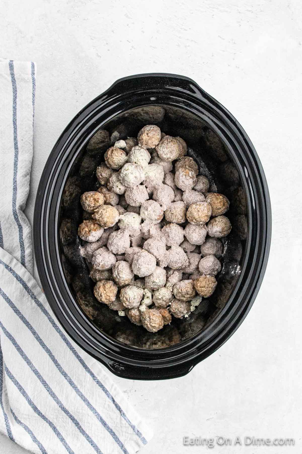 Topping the frozen meatballs with the seasoning in the slow cooker