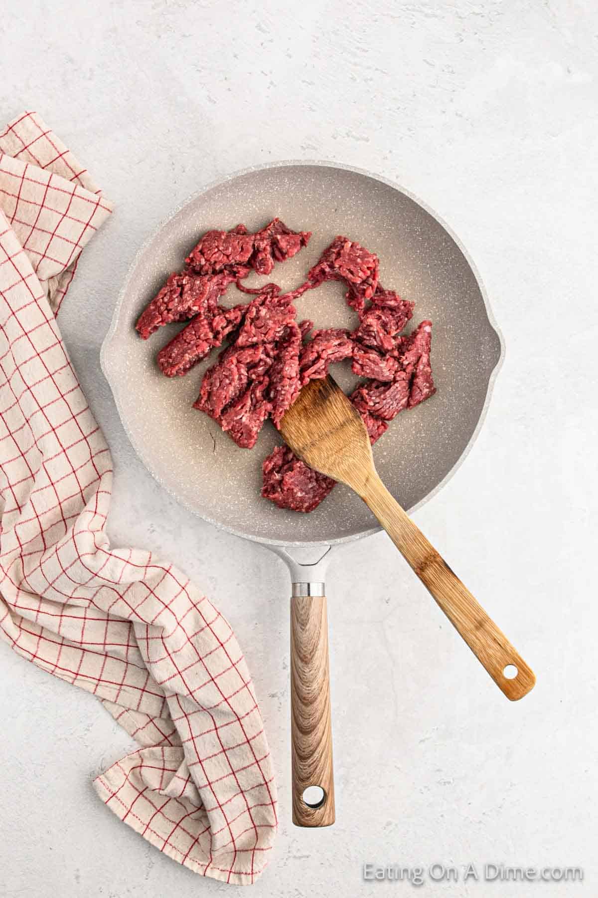 Cooking ground beef in a skillet with wooden spoon