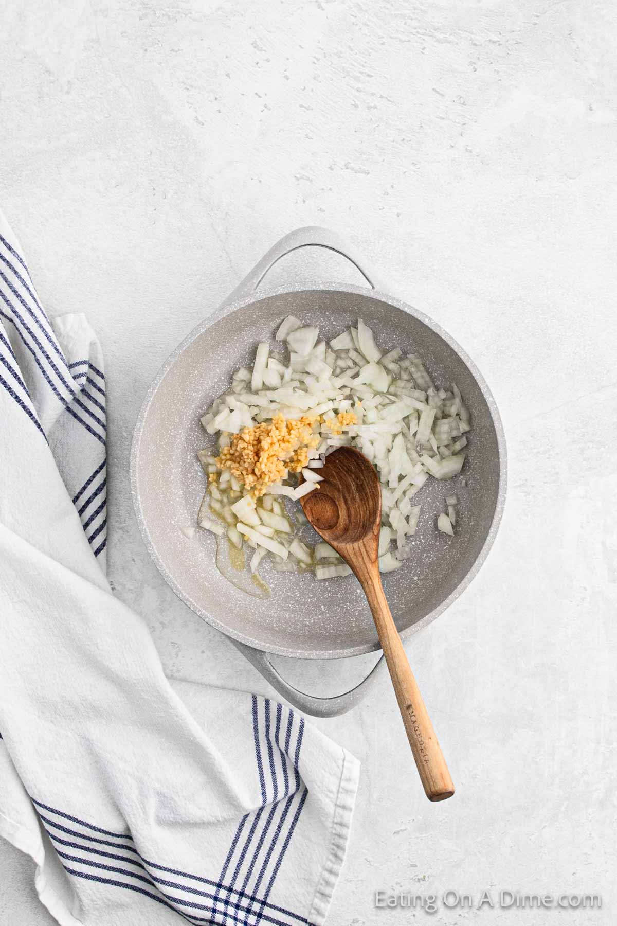 Cooking diced onions and minced garlic in a large pot with a wooden spoon