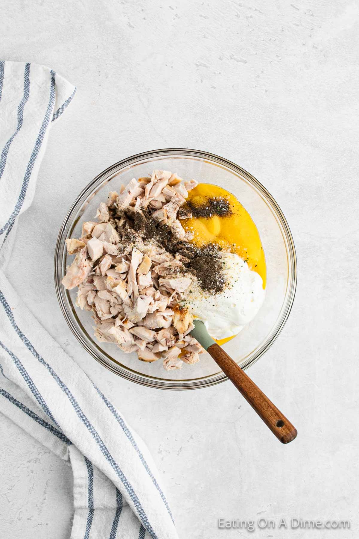 Combining shredded cooked chicken in a bowl with cream of chicken soup, sour cream and seasoning