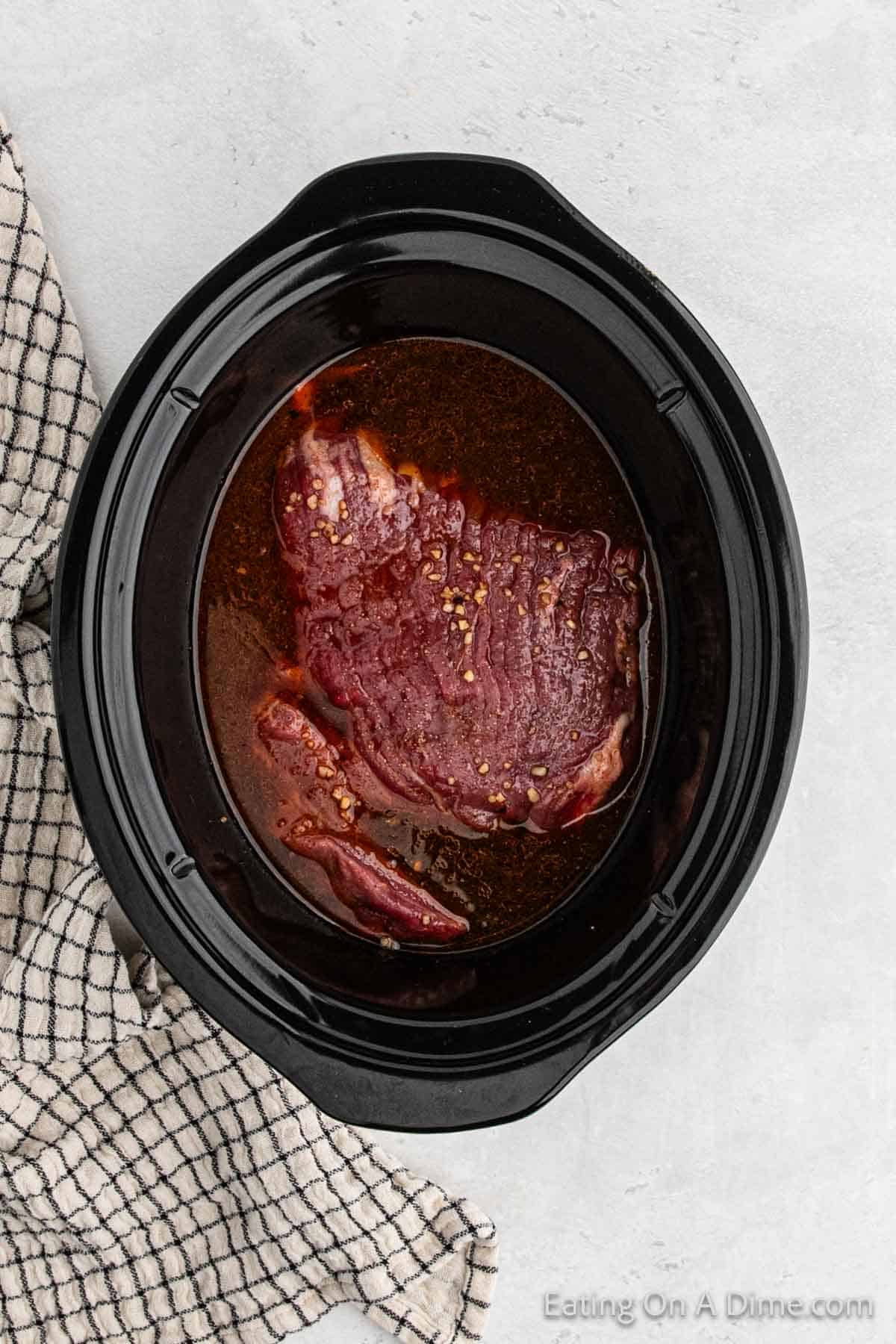 Flank steak in the slow cooker topped with the sauce ingredients