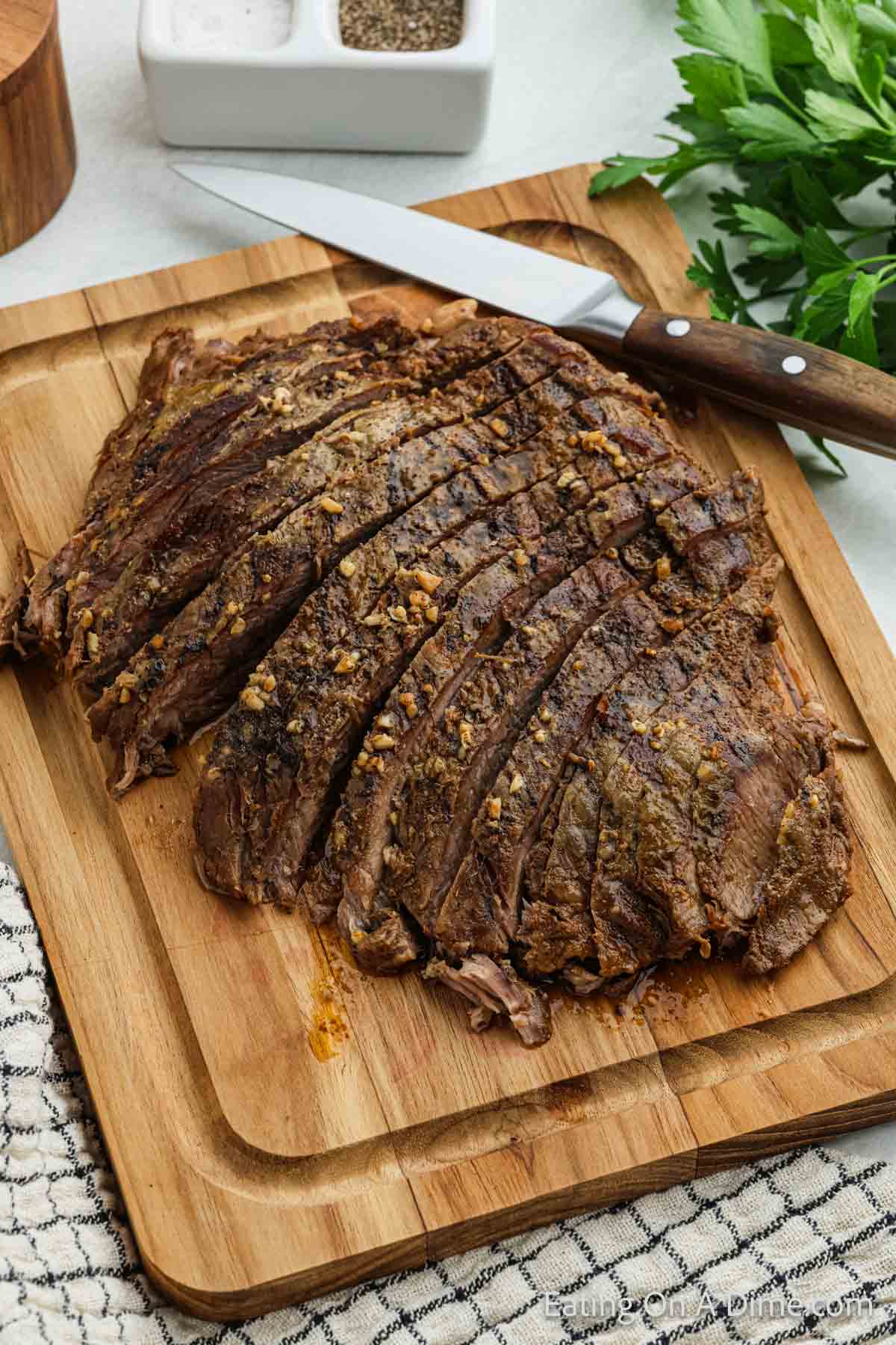 Sliced Cooked Flank Steak on a cutting board with a knife