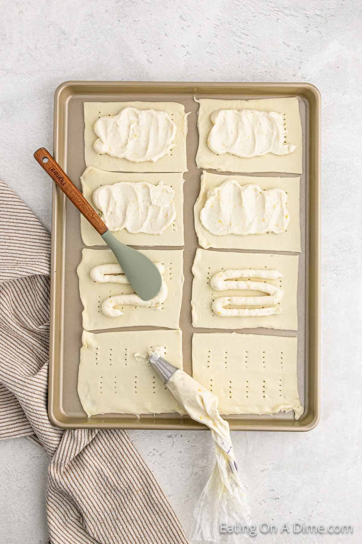 Spreading cream cheese mixture on a puff pastry on a baking sheet