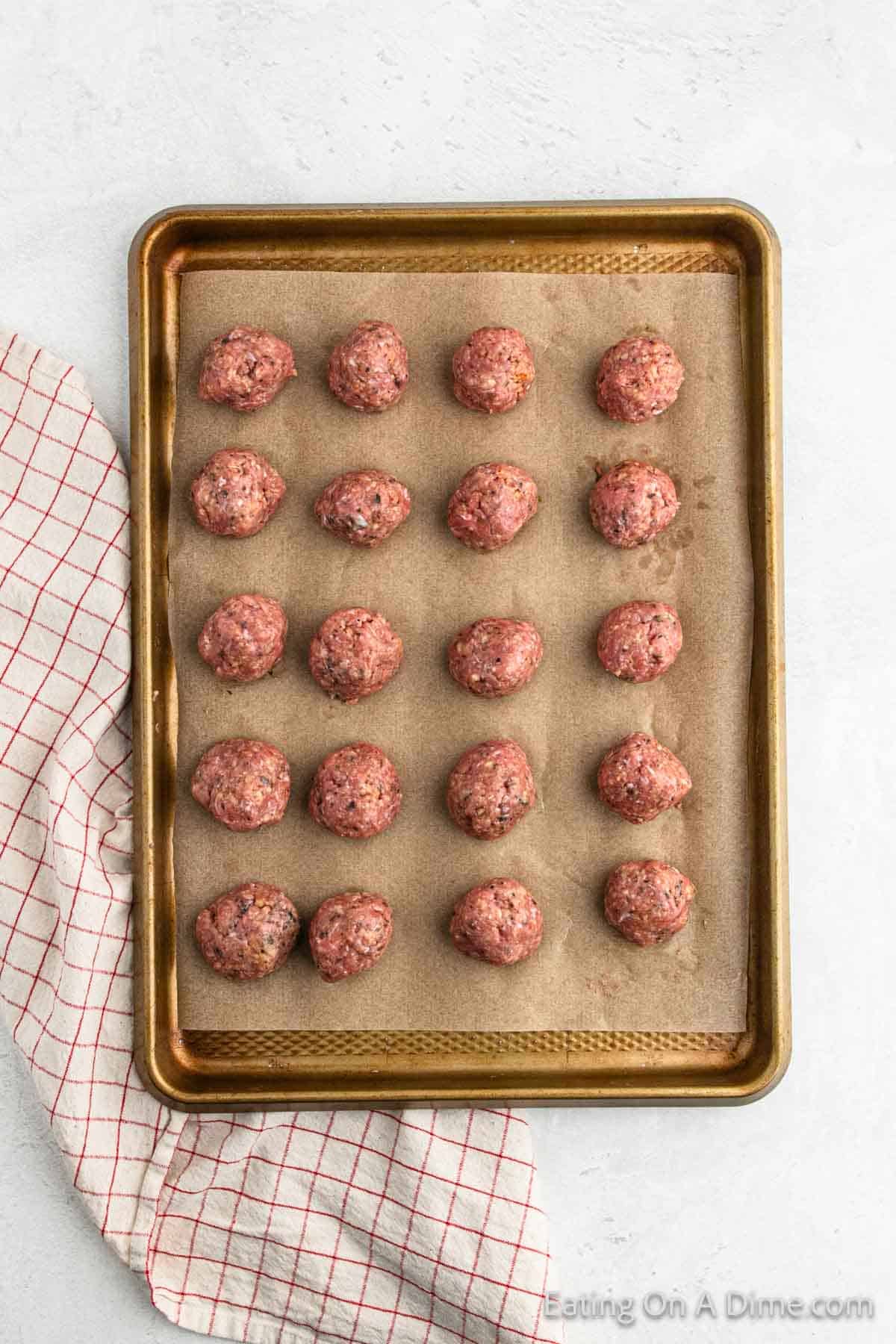 Uncooked turkey meatballs on a baking sheet lined with parchment paper