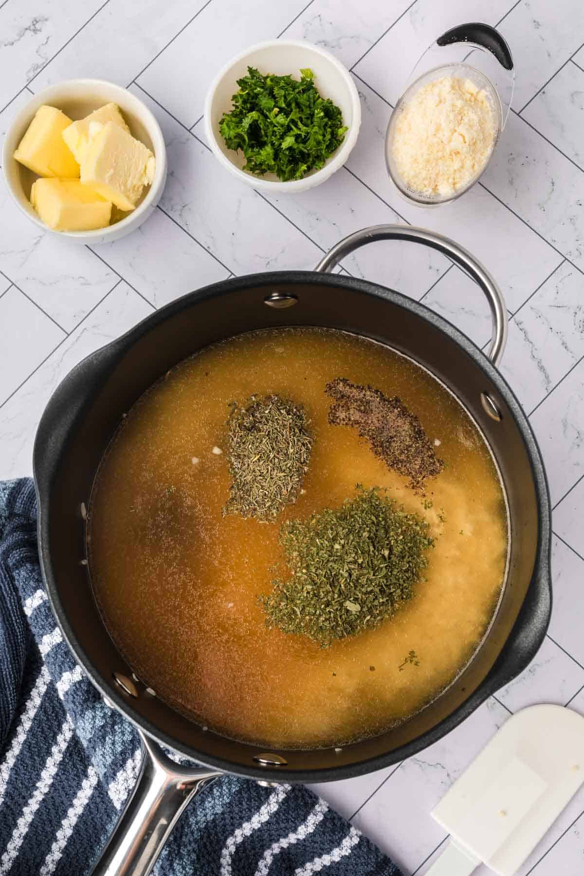 Adding chicken broth and seasoning in the sauce pan with rice