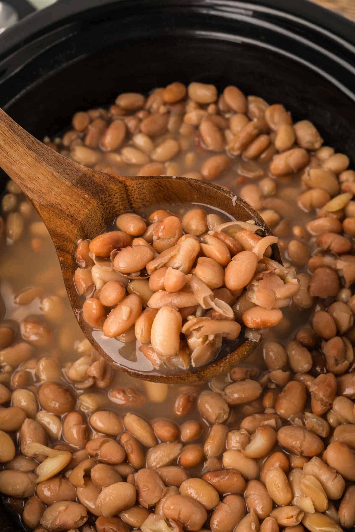 Brown beans in the slow cooker with a serving in a ladle