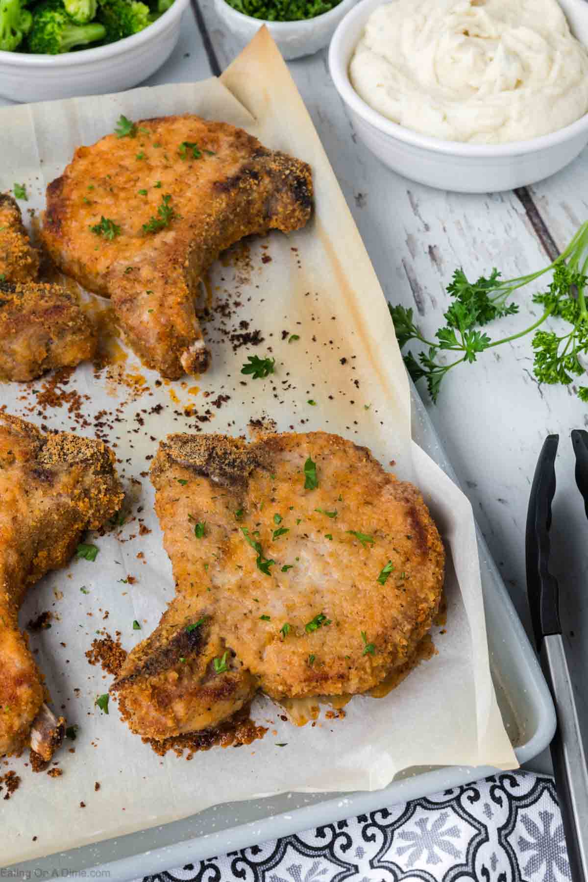 Shake and Bake pork chops on a baking sheet lined with parchment paper