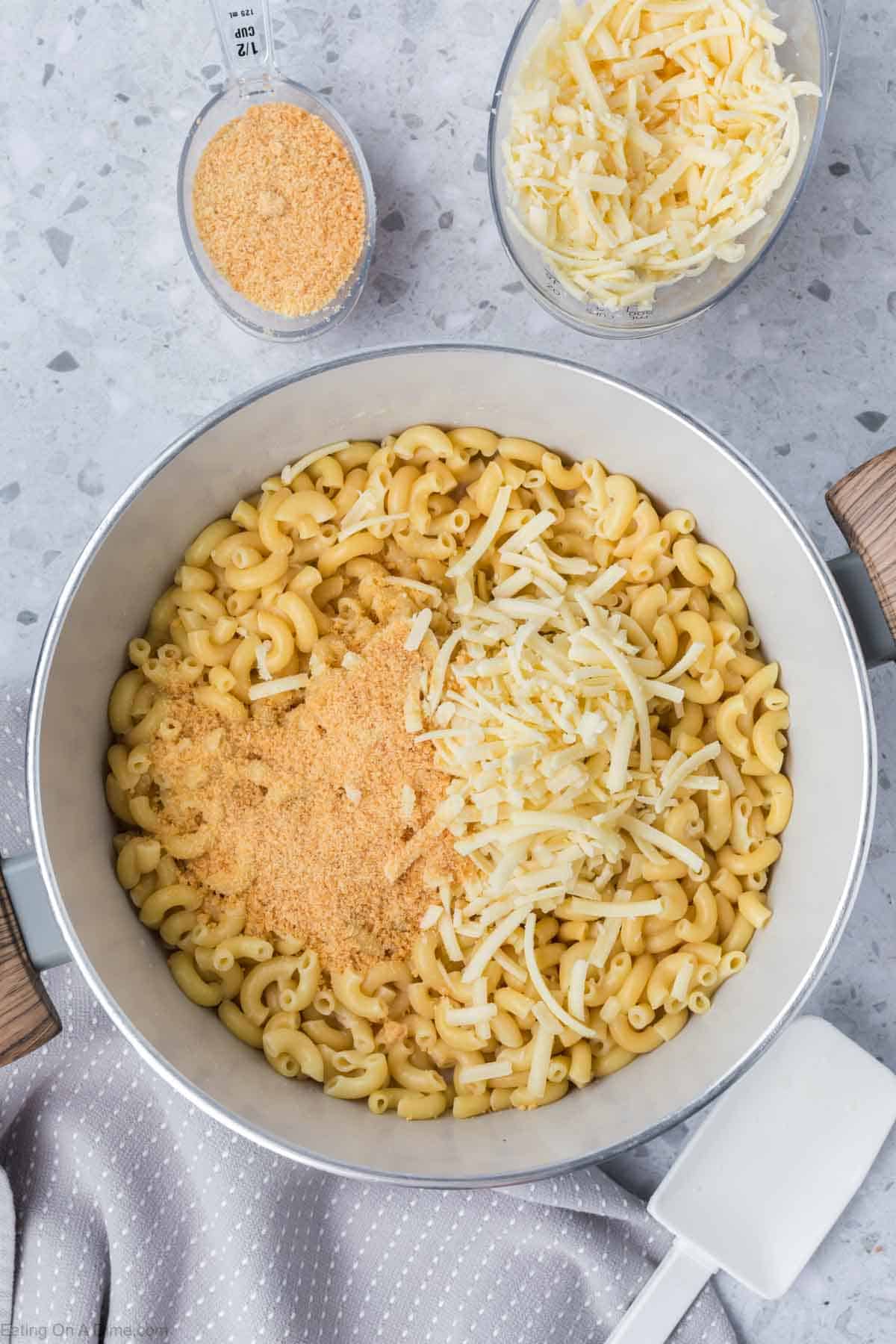 Topping the mac and cheese mixture with shredded cheese