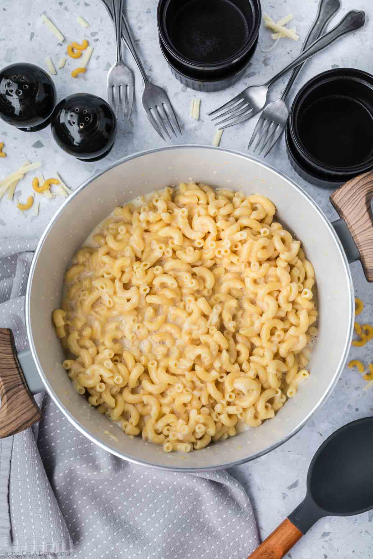 Combining the shredded cheese with the mac and cheese mixture in a large pot