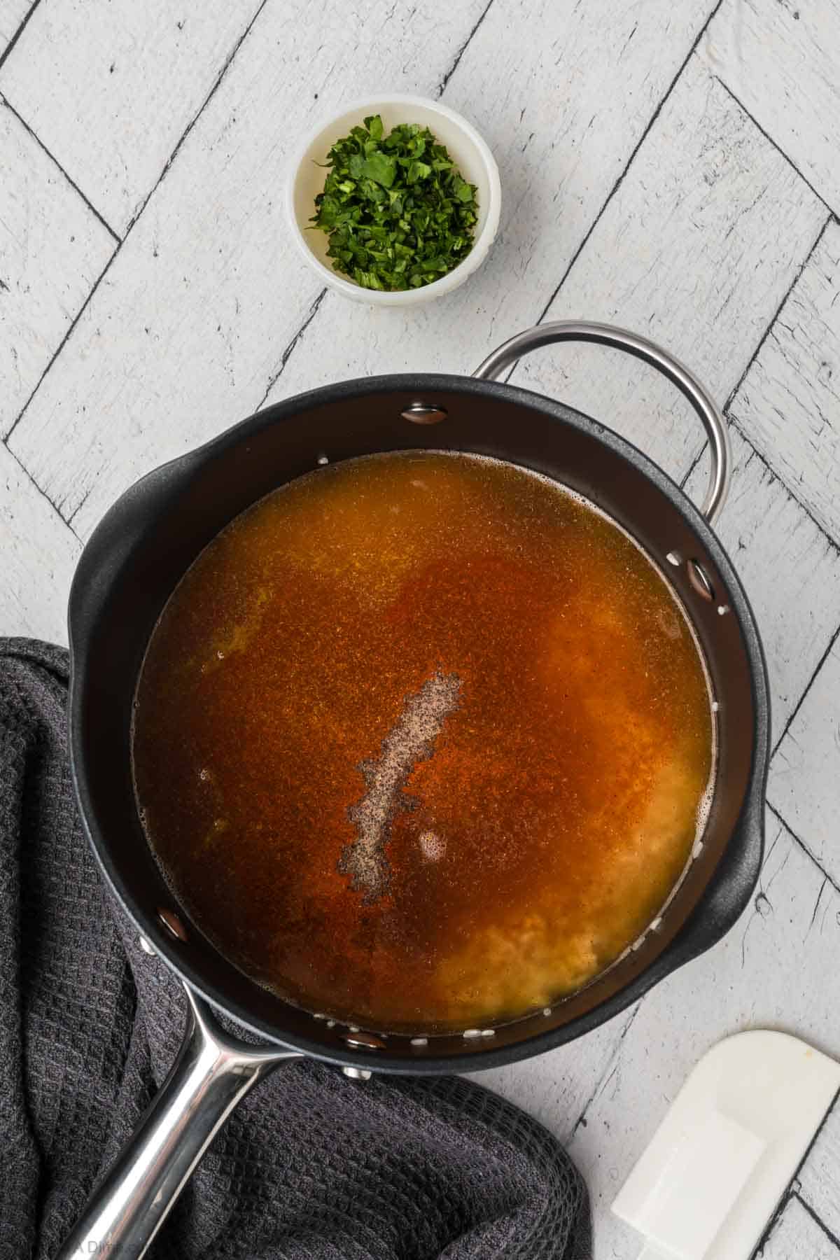 Chicken broth and spices poured into the saucepan with the rice