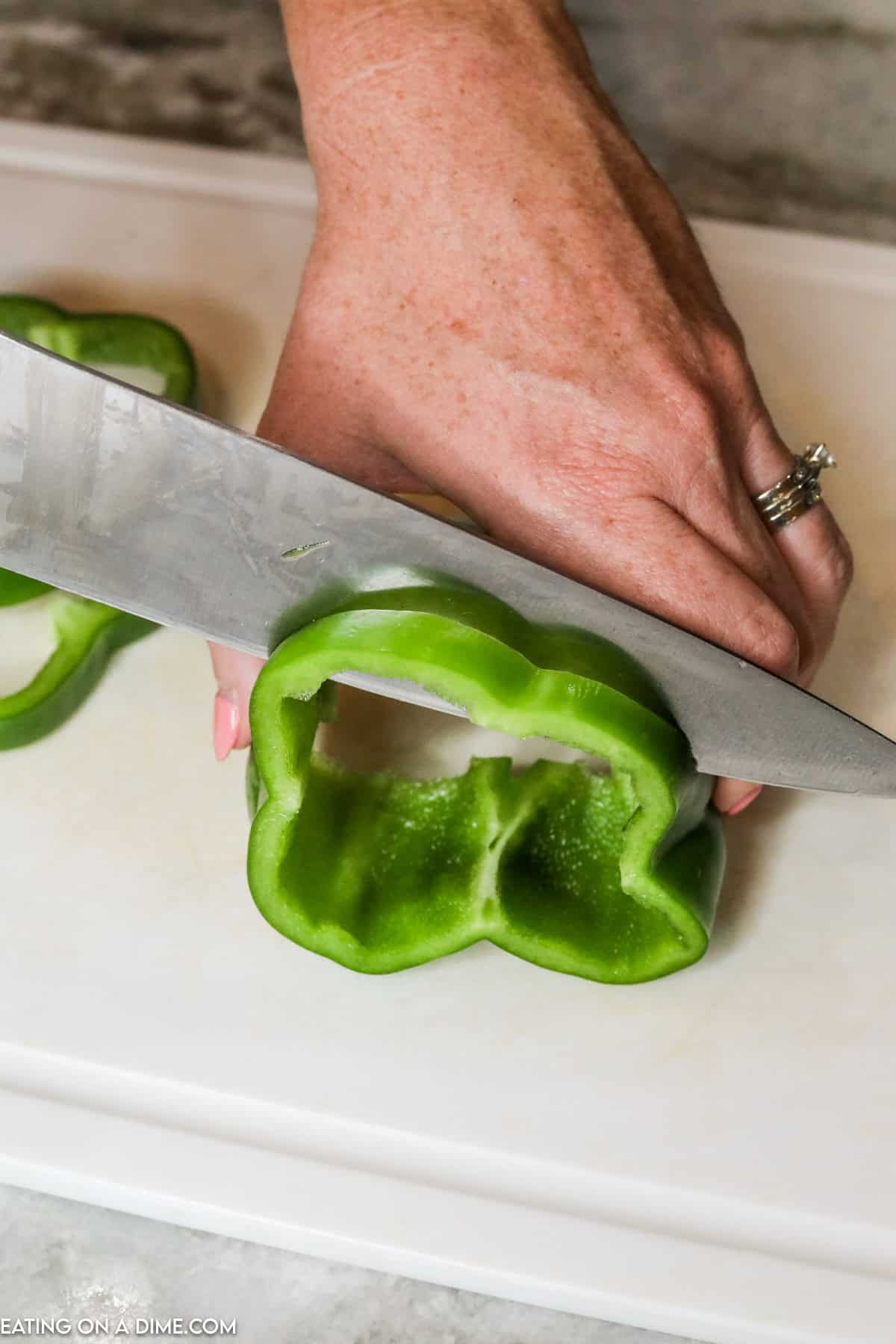 Slicing the bell pepper in rings with a knife on a cutting board