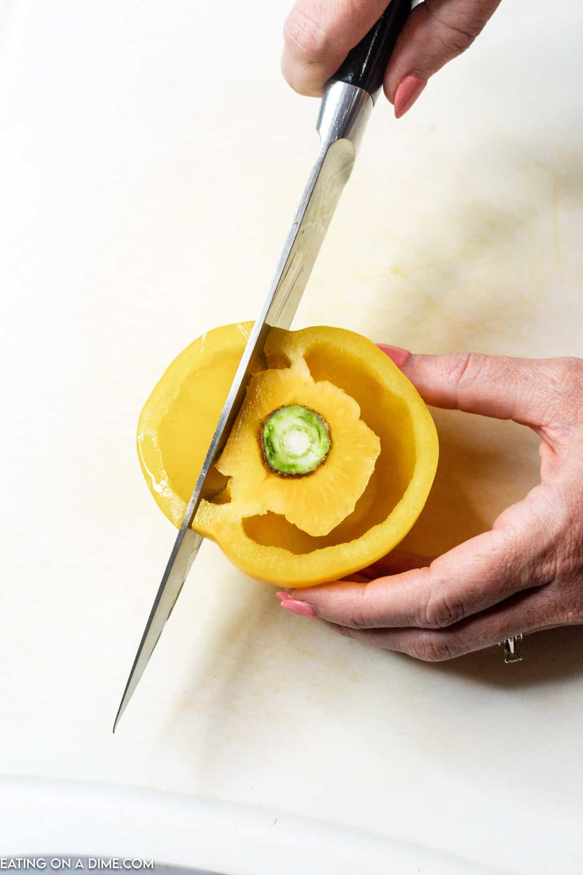 Slicing the sides of the yellow bell pepper with a knife