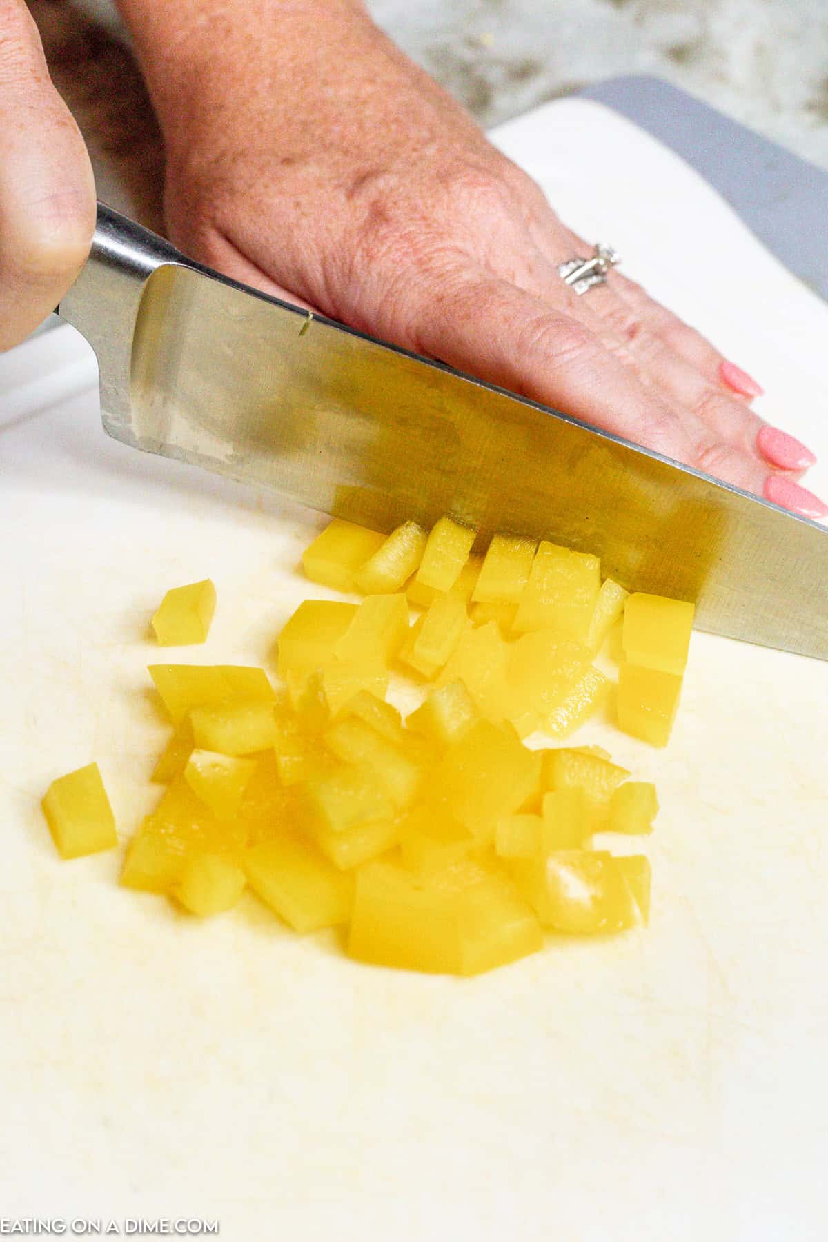 Cutting the bell pepper into bite size pieces of a knife on a cutting board