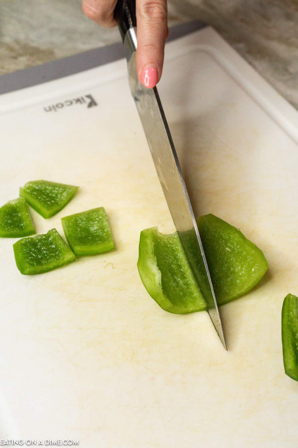 Cutting the green bell pepper into quarter pieces