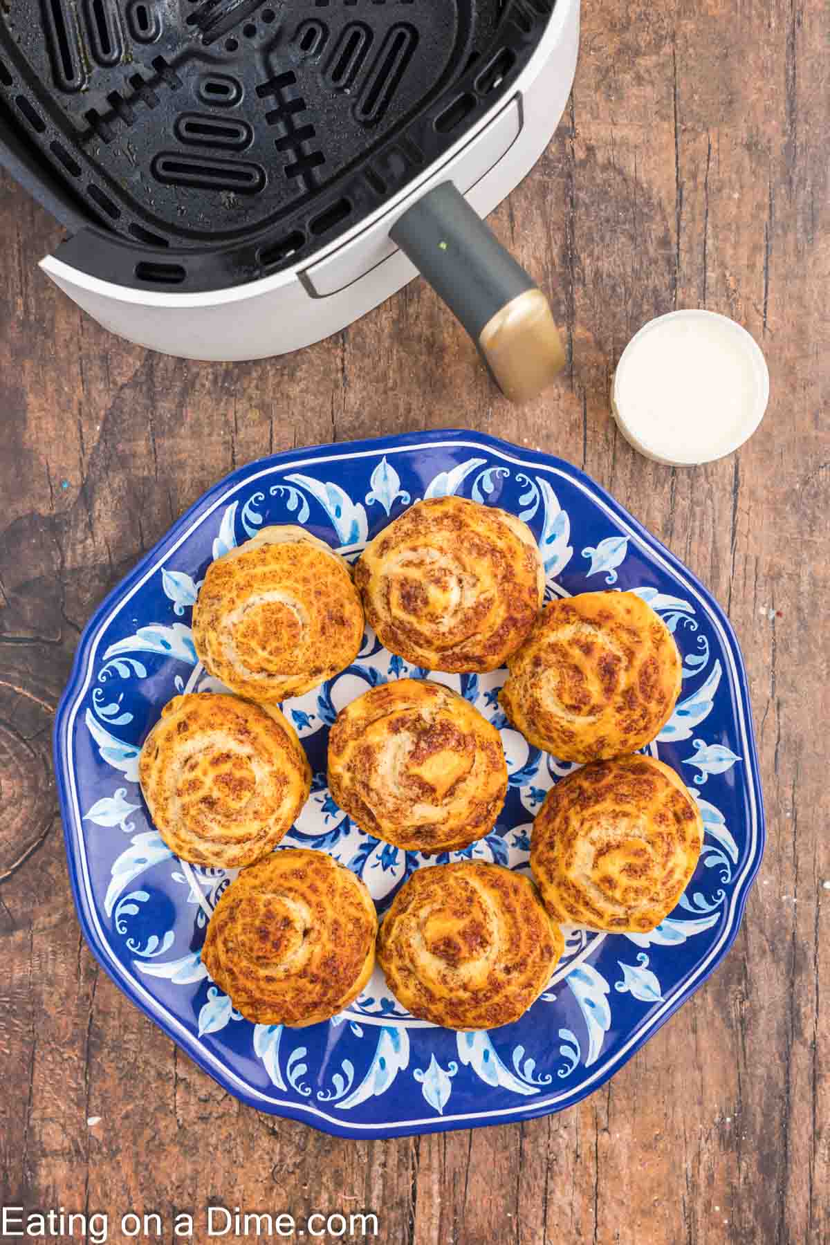 Cooked cinnamon rolls on a plate with the container of icing on the side