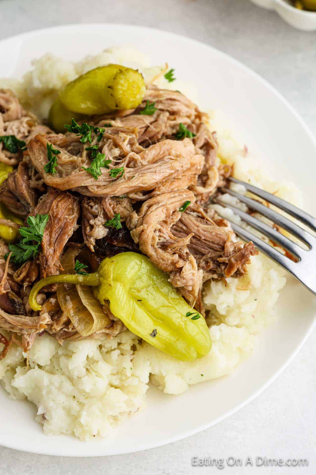 Shredded pork roast on a plate of mashed potatoes