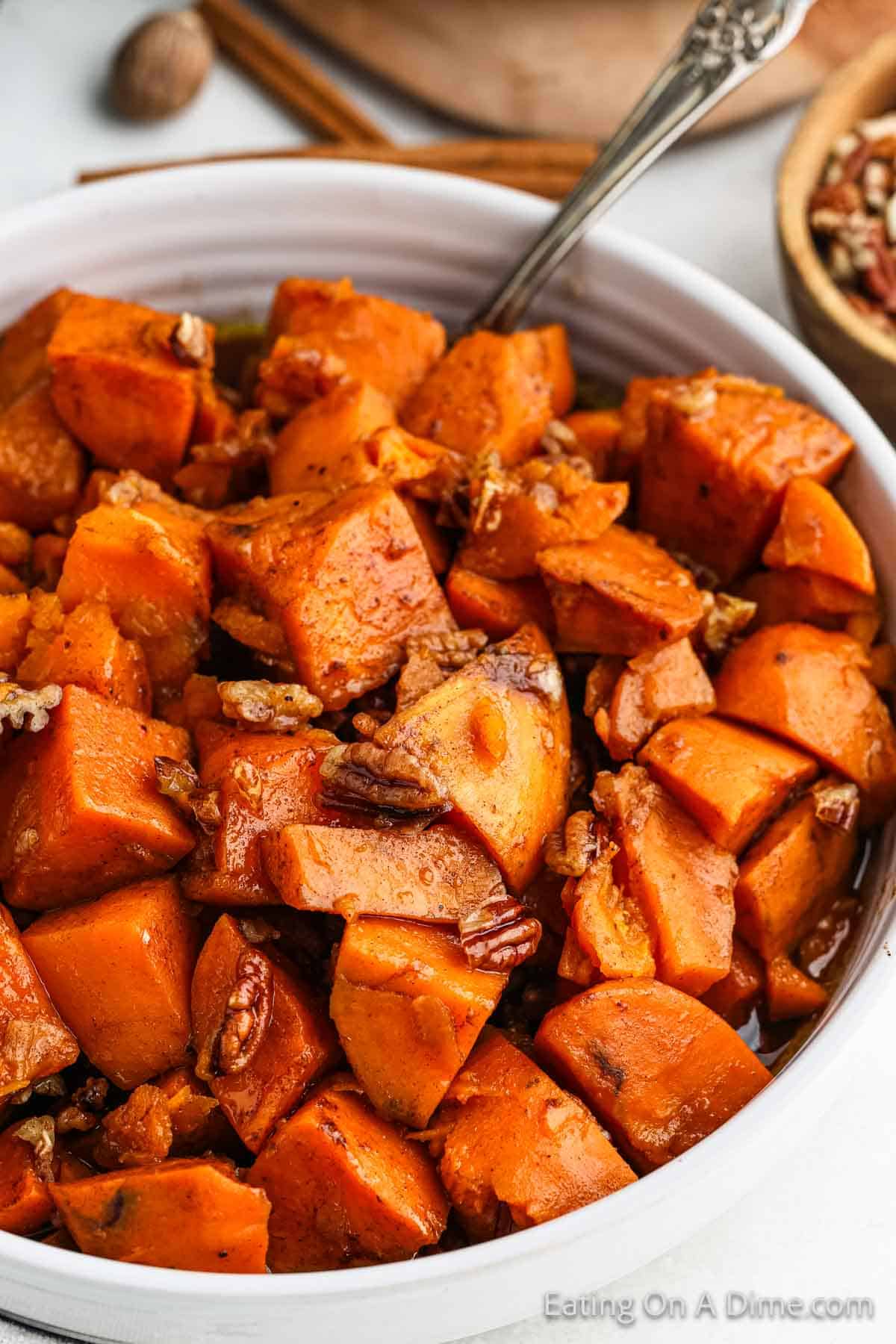 Candied Sweet Potatoes in a bowl topped with chopped pecans