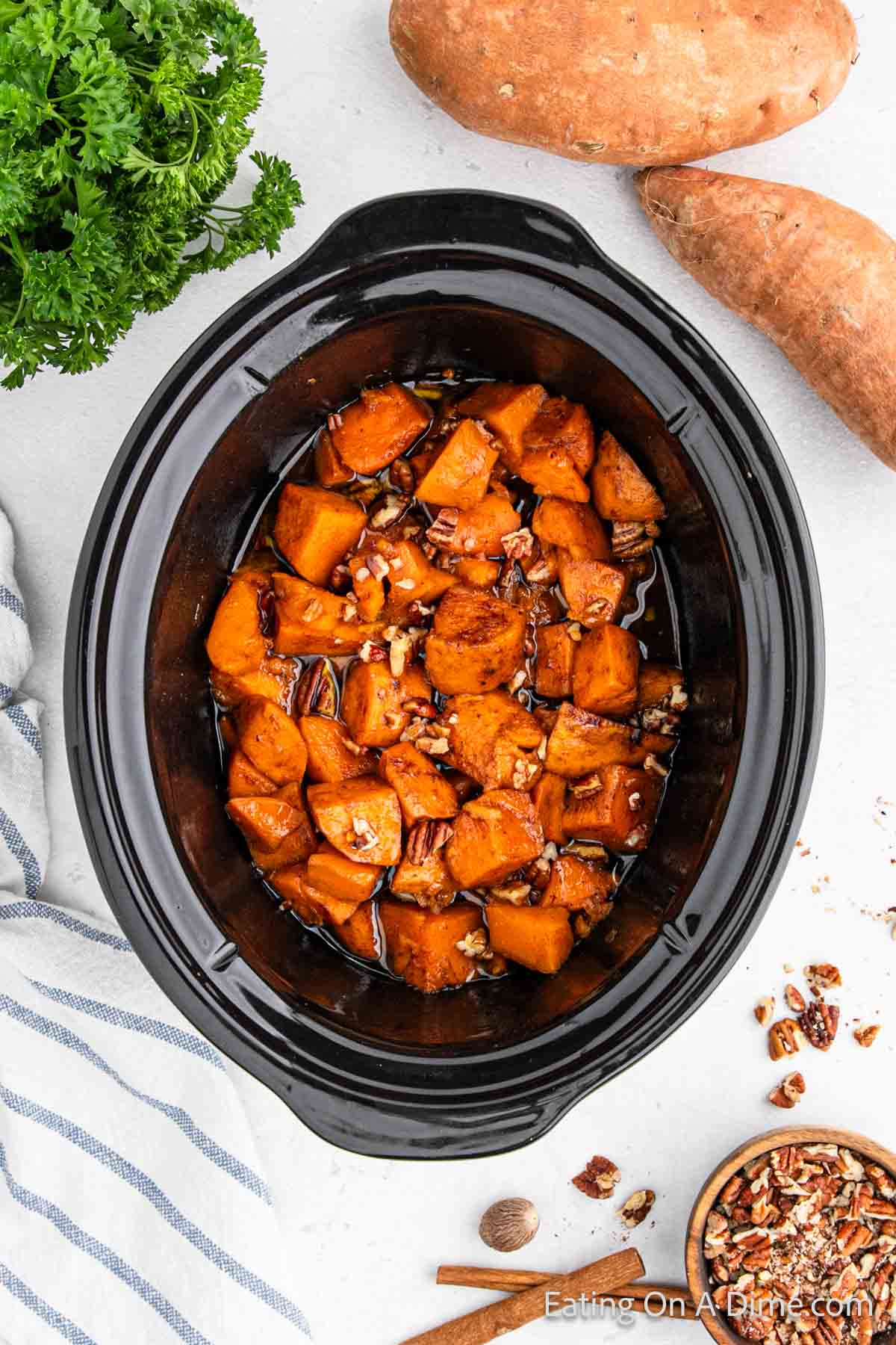 Diced Sweet Potatoes in the slow cooker cooked in a sweet glaze topped with chopped pecans