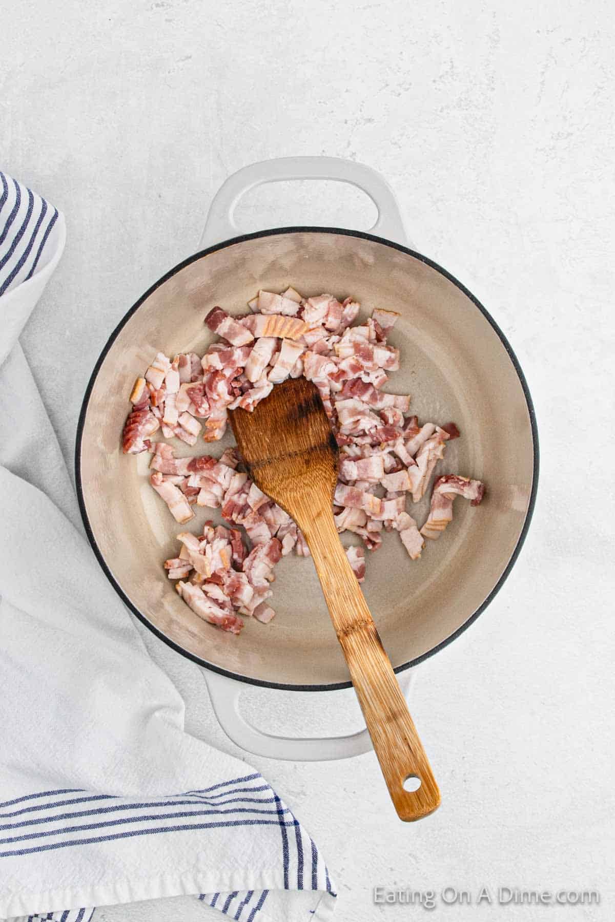 Cooking chopped bacon in the large pot with a wooden spoon