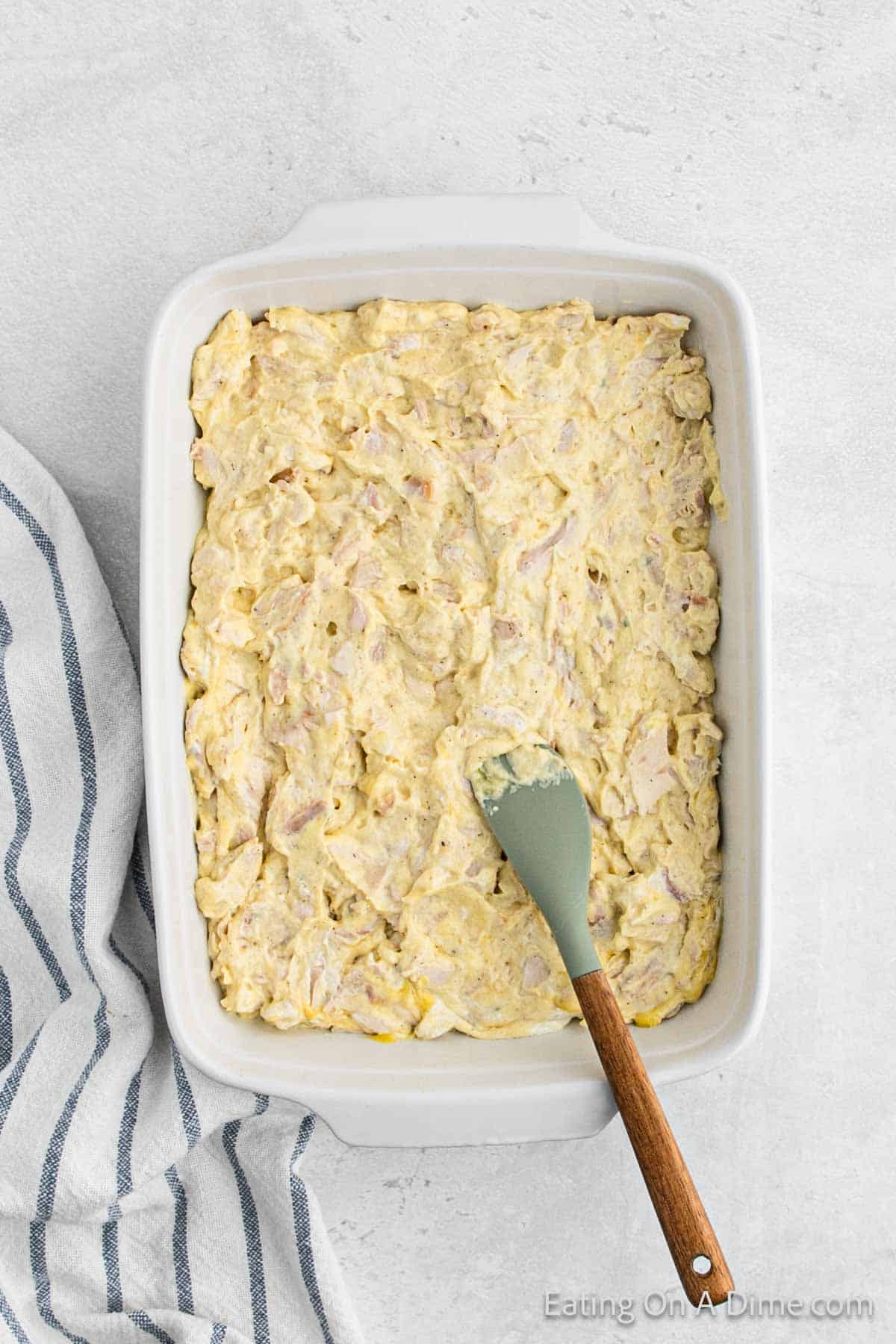 Spreading the chicken mixture in a casserole dish with a spatula