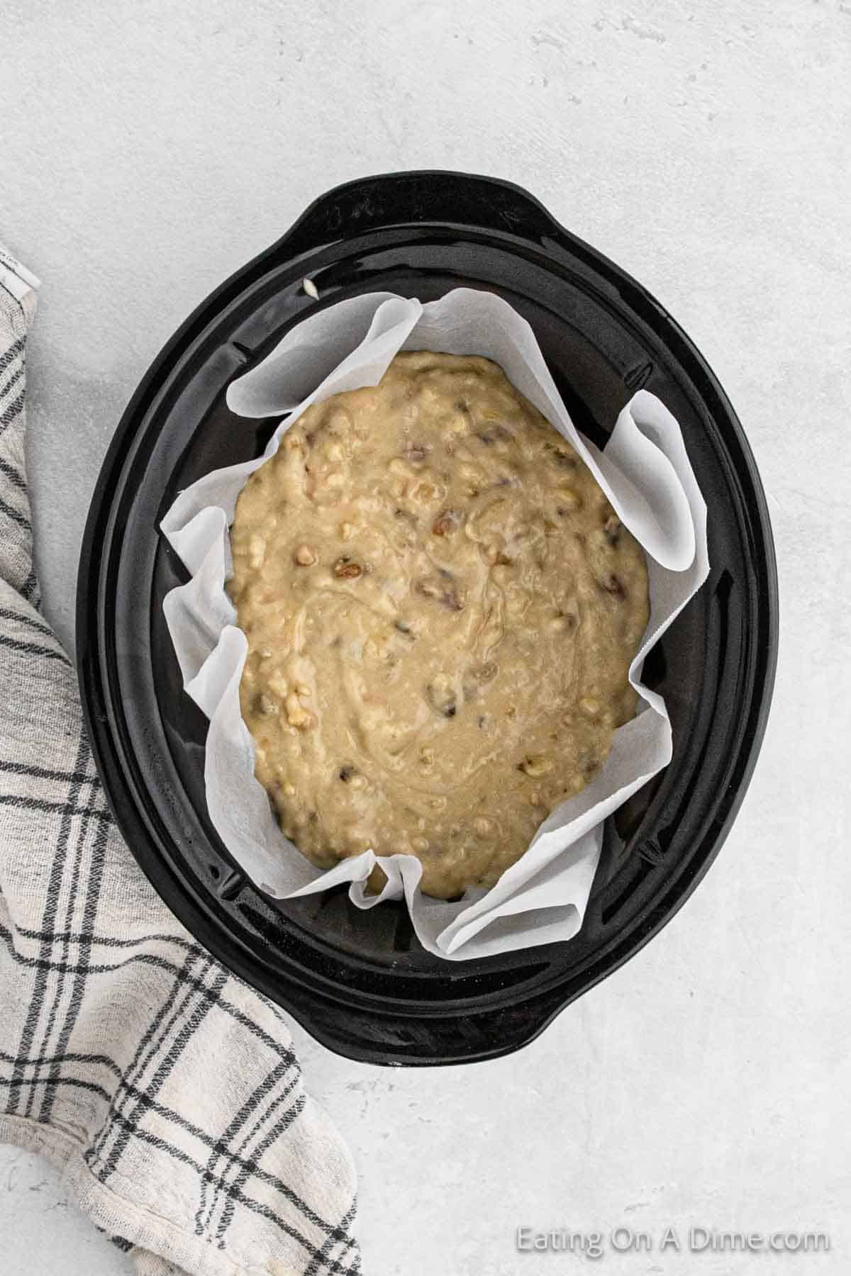 Banana bread batter placed in slow cooker lined with parchment paper