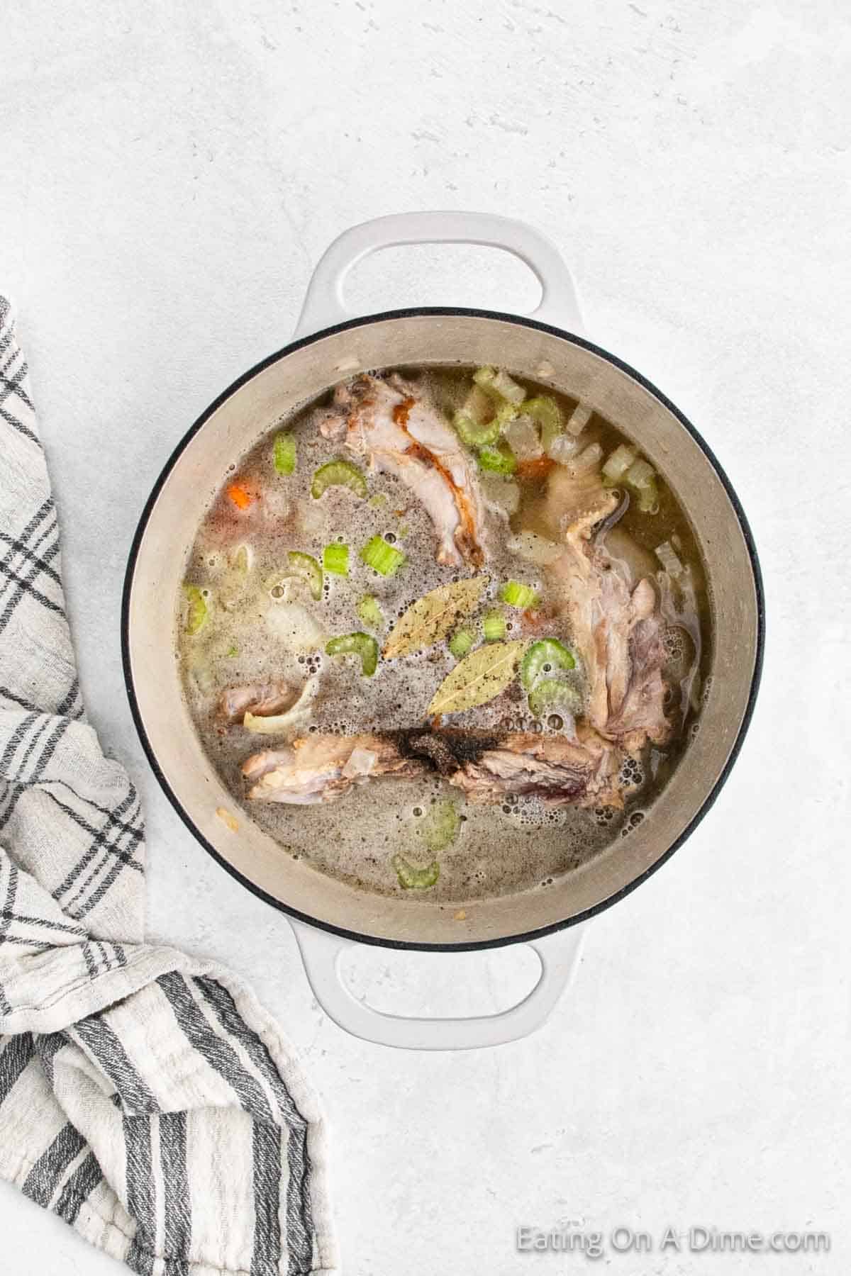 Broth poured in a large pot with the turkey neck, celery and carrots