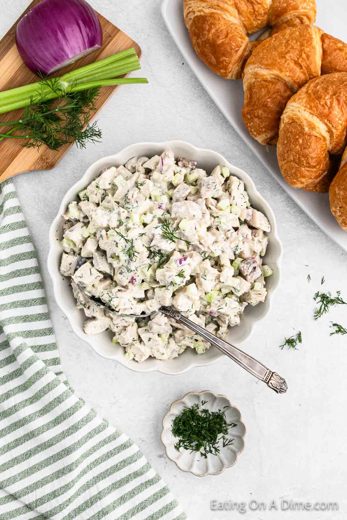 Turkey Salad in a bowl with a side of fresh dill and a platter of croissants